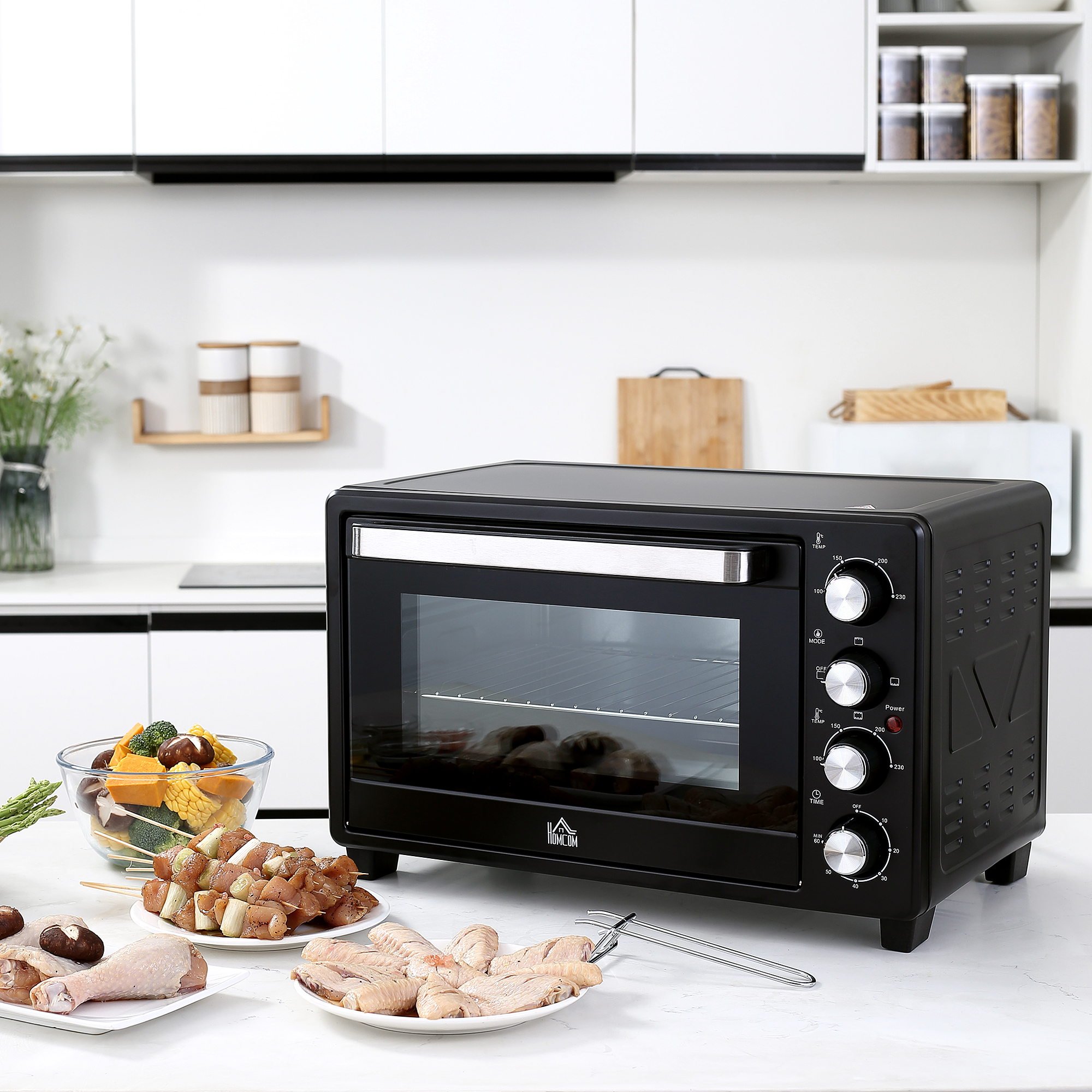 Horno negro con comida dentro y en la encimera. Gabinetes blancos en el fondo.