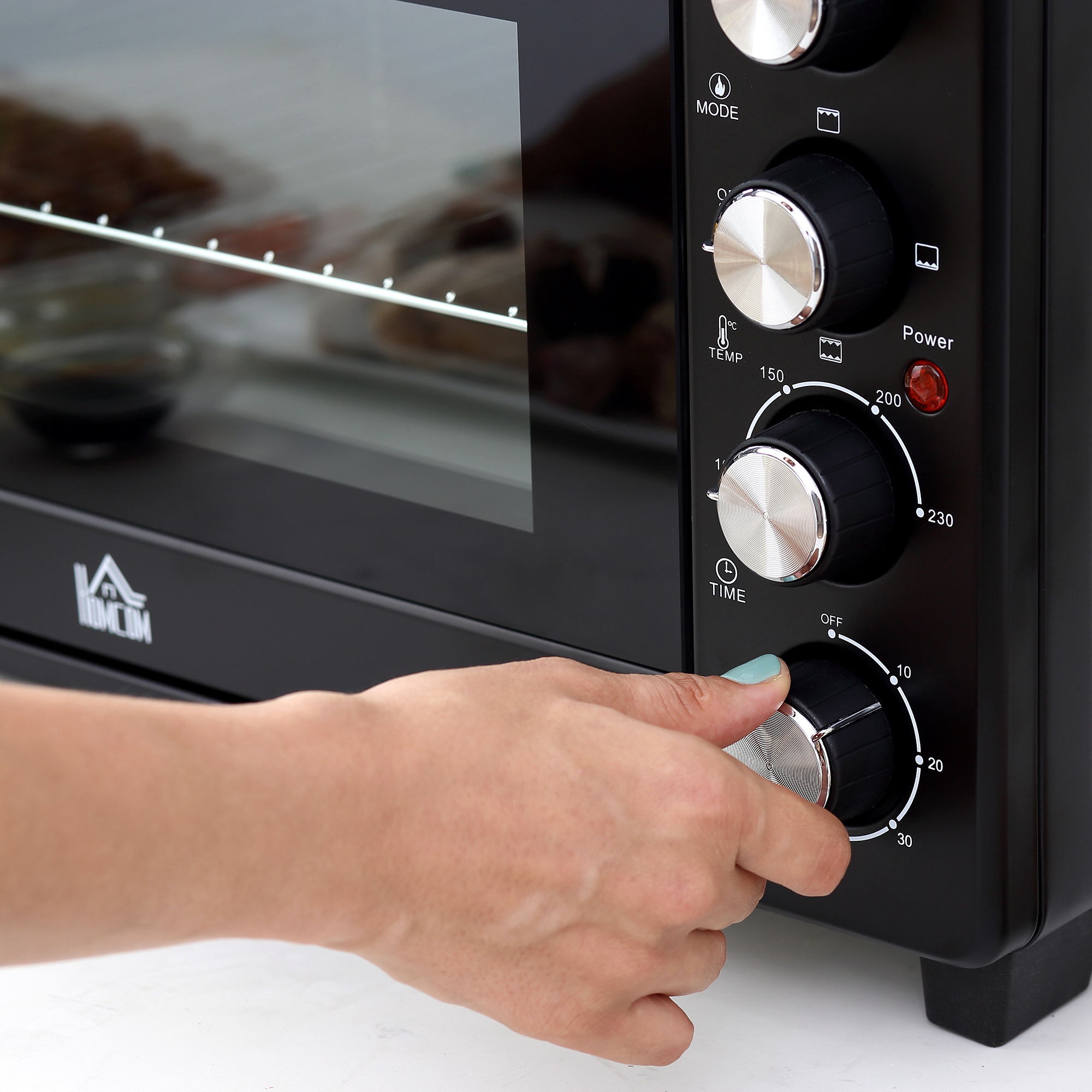La mano de una mujer está girando un dial en un horno negro.