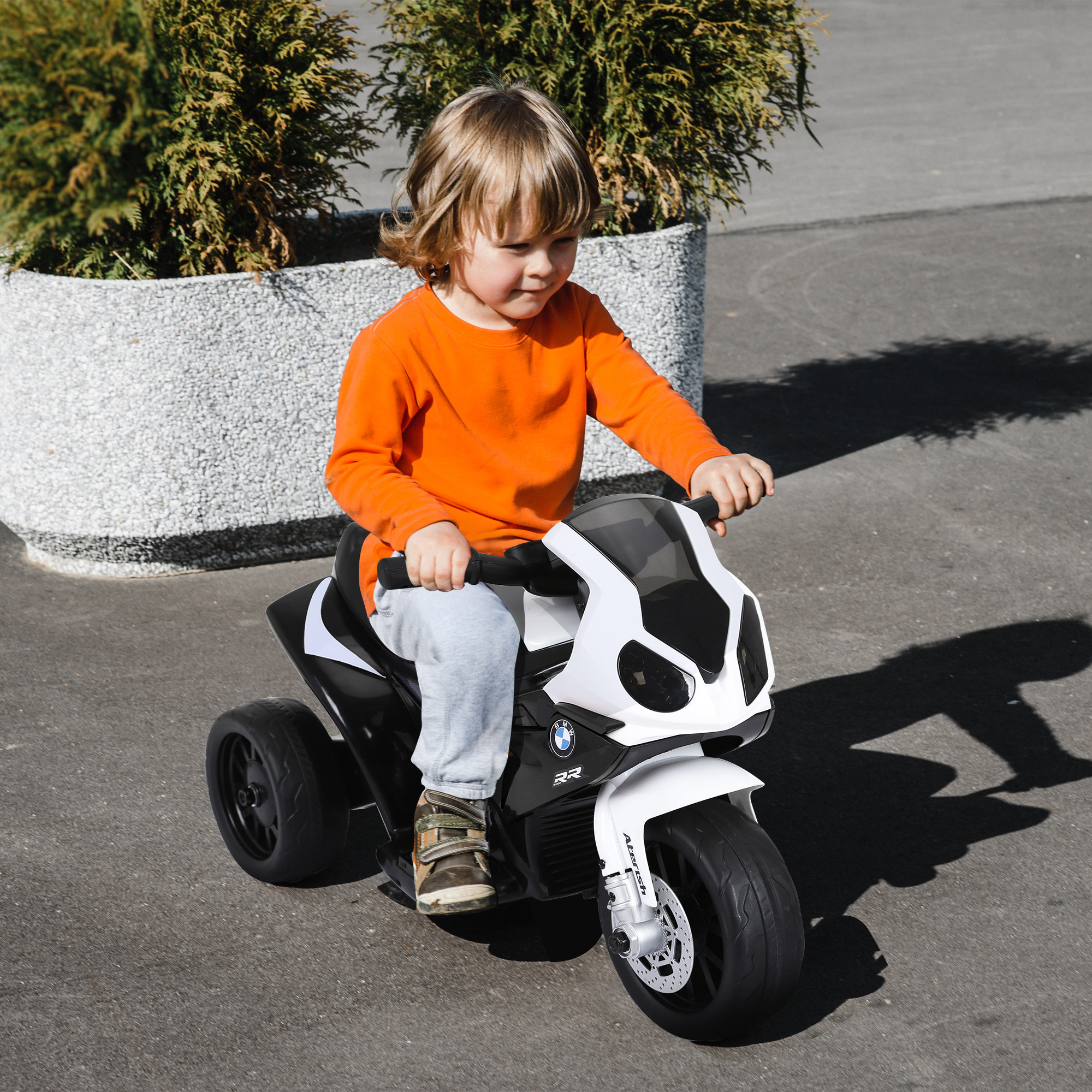Un niño pequeño en una moto de juguete, montando al aire libre.