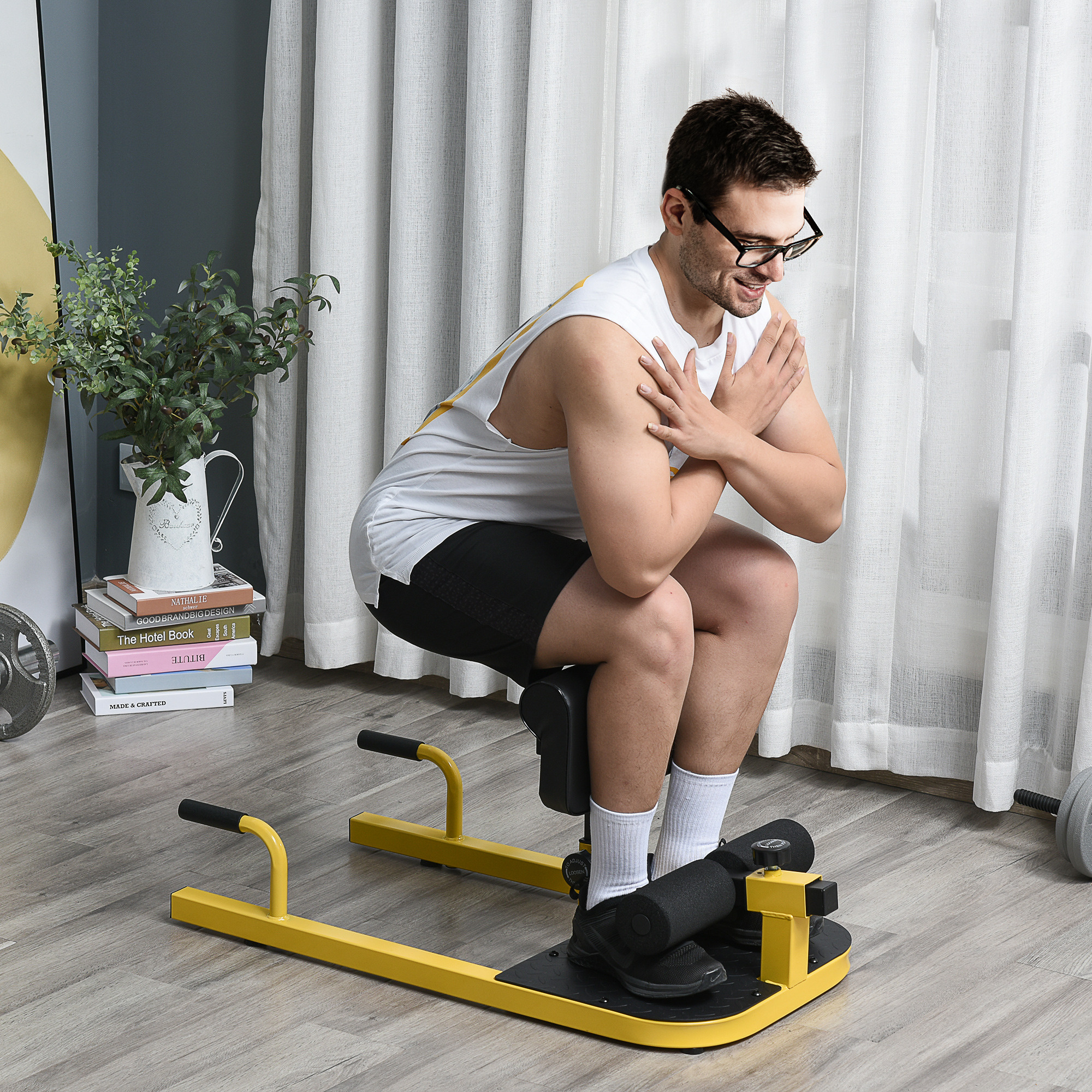 Uomo con occhiali che usa una macchina per squat in una stanza con una pianta e una tenda.