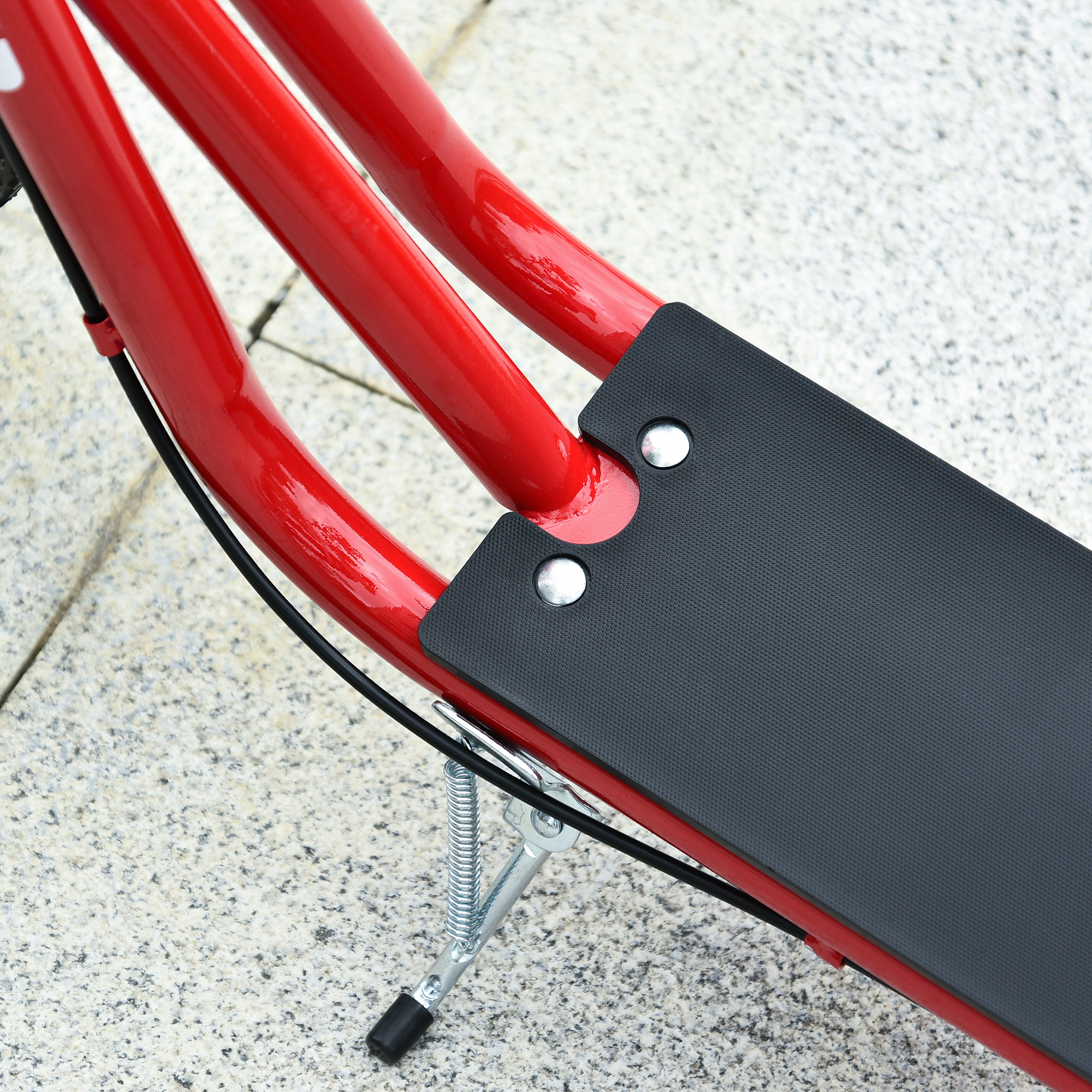 Primer plano de un cuadro de scooter rojo con una plataforma negra sobre una superficie pavimentada.