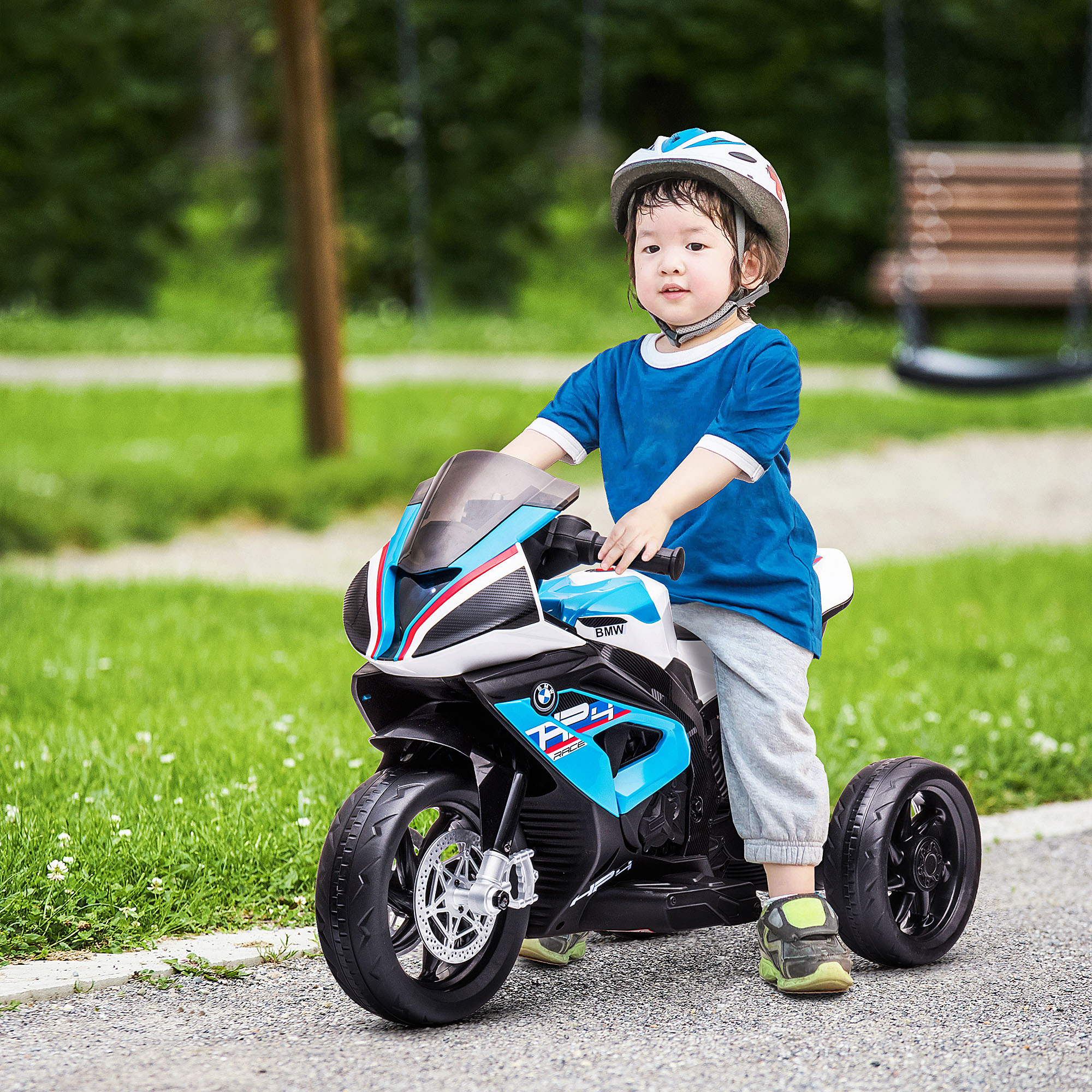 Un niño en una moto de juguete azul y blanca, usando un casco.