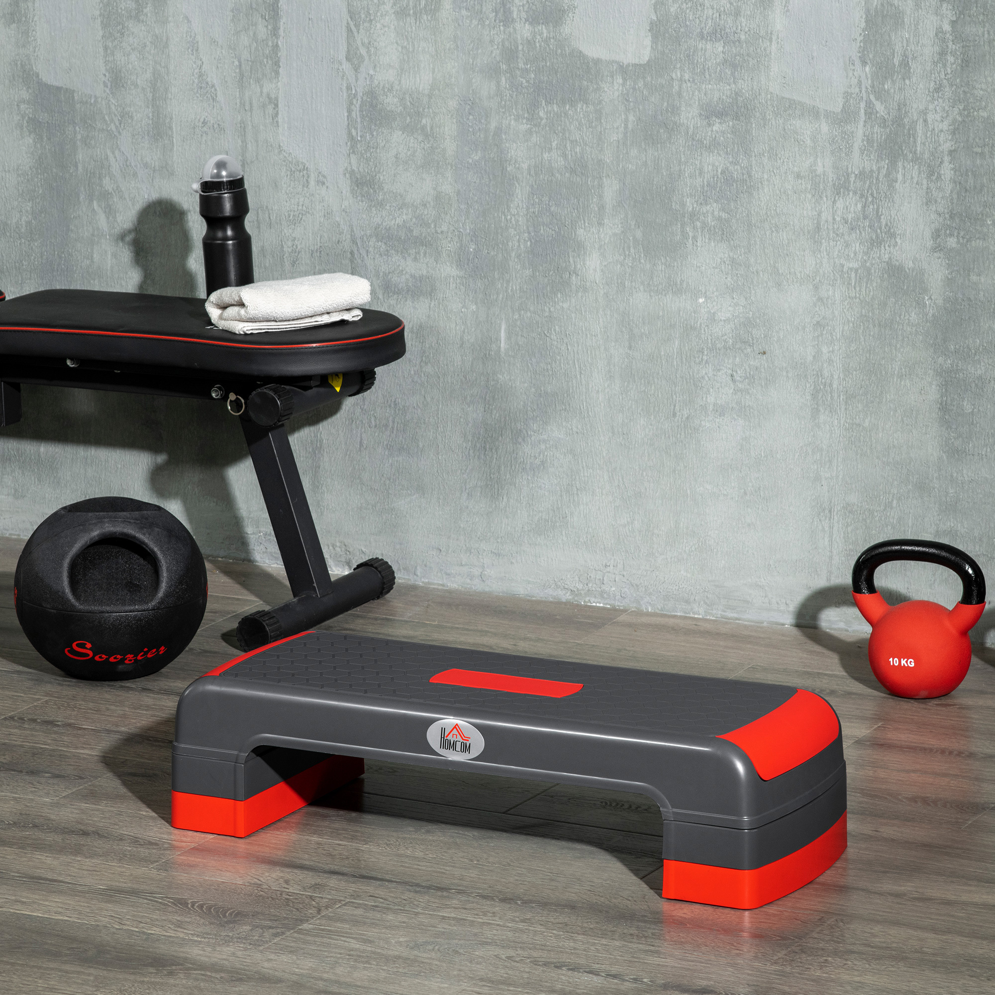Attrezzatura da palestra in una stanza. Include panca, step, palla medica e kettlebell.