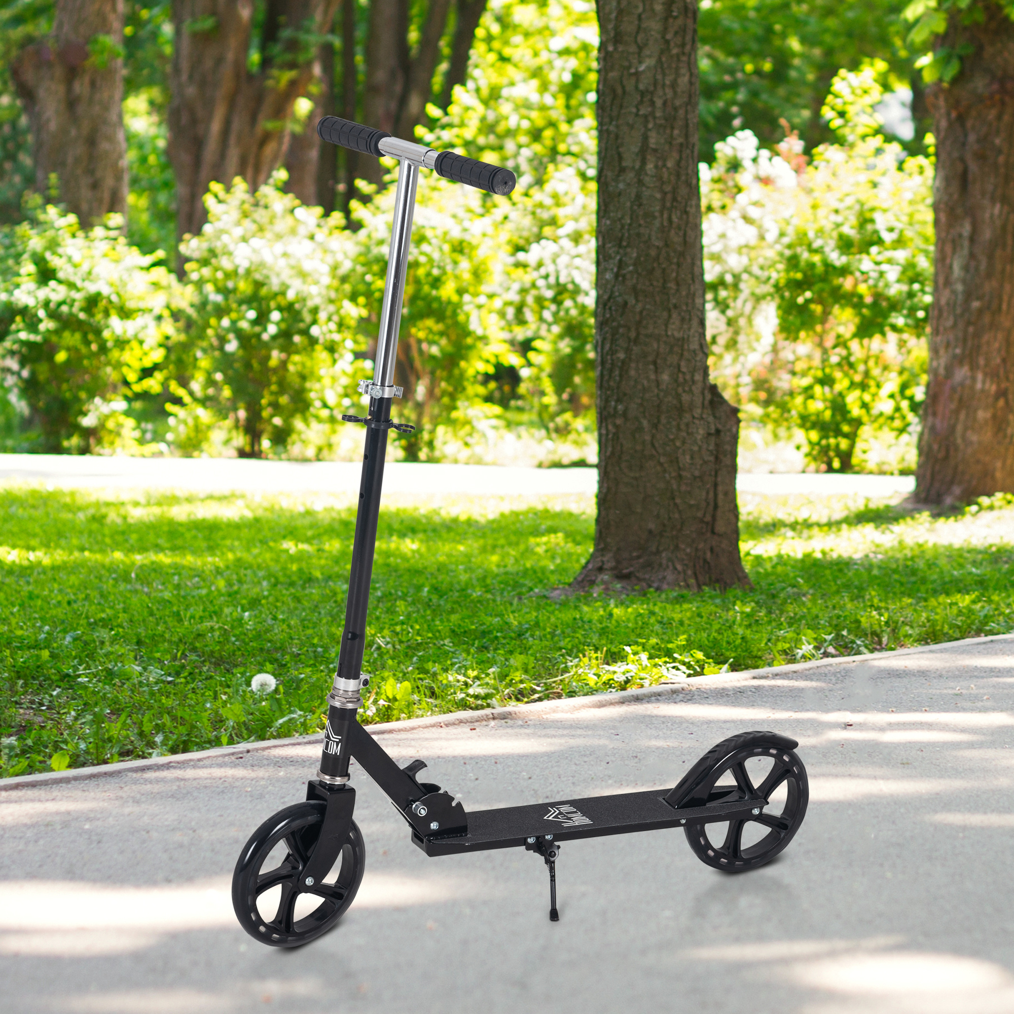 Scooter negro en un camino pavimentado en un parque, con hierba verde y árboles en el fondo en un día soleado.