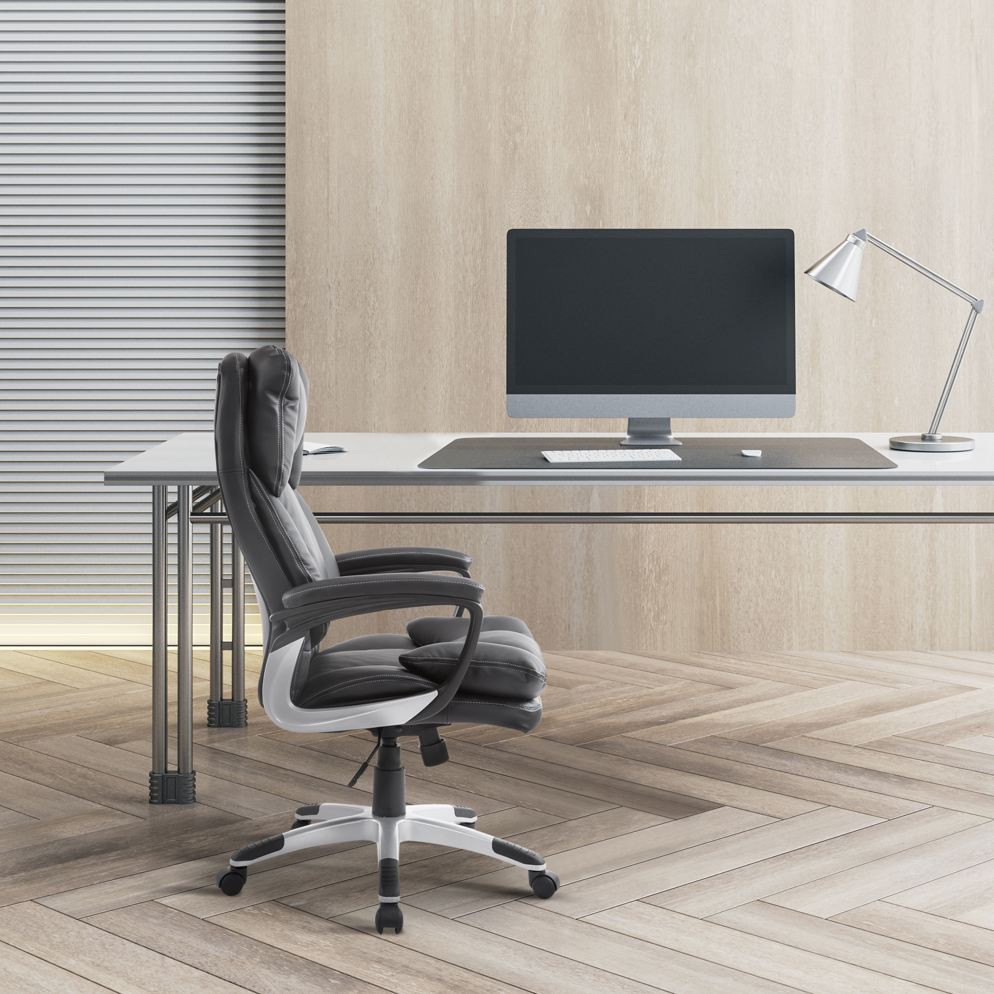 Configuración de oficina: silla de cuero negra, escritorio con ordenador, lámpara.