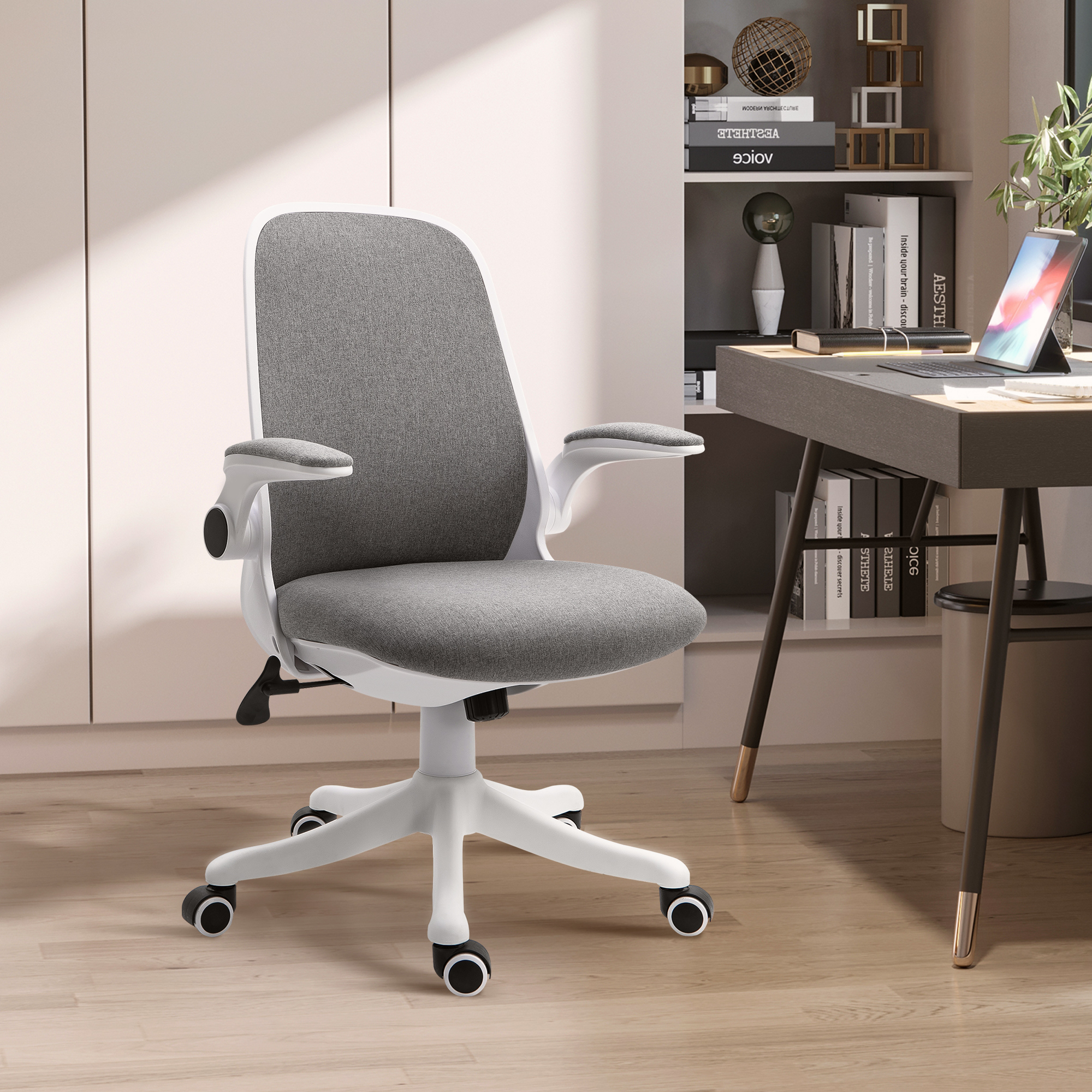 Silla de oficina blanca con asiento de tela gris. Un escritorio con portátil en el fondo.