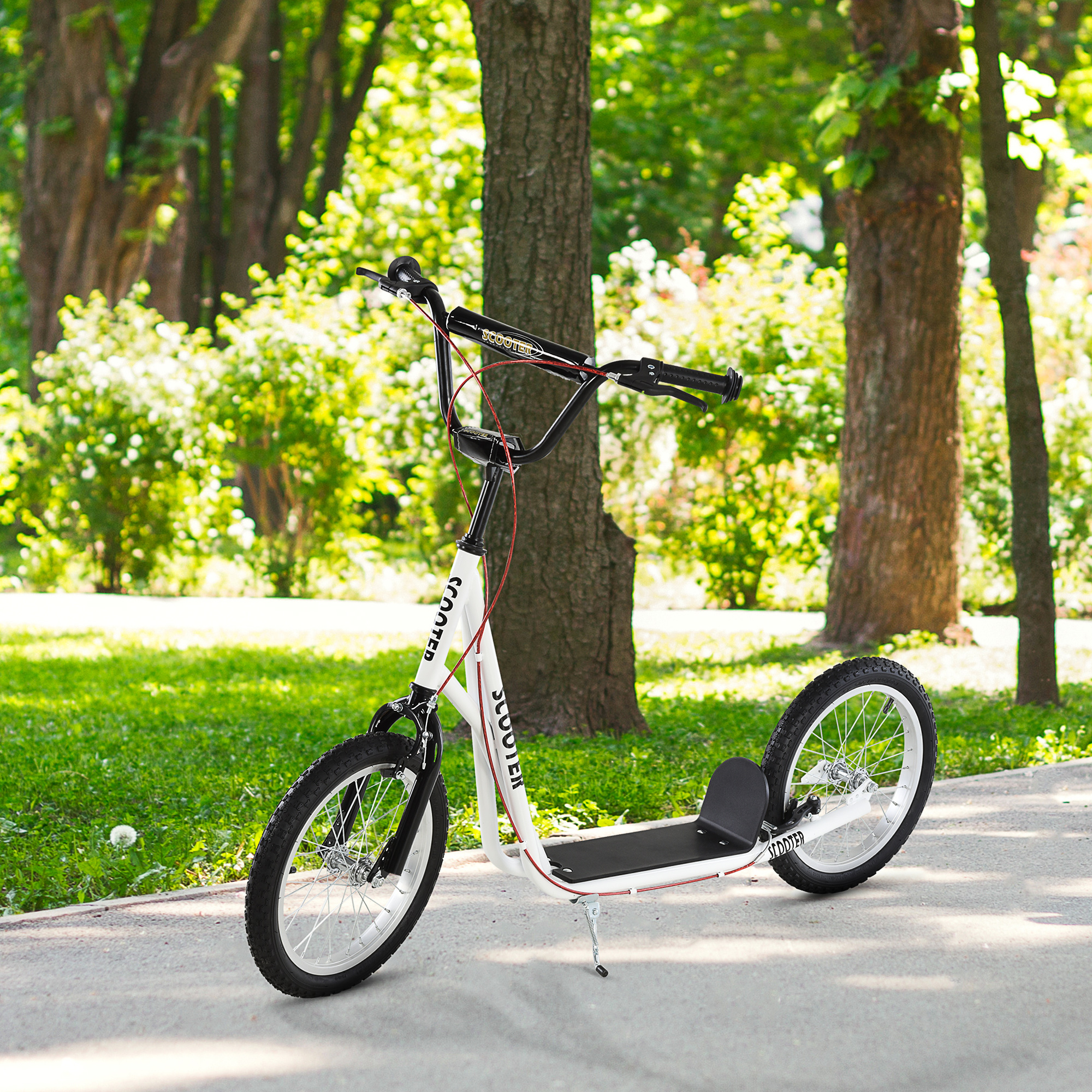 Scooter blanco y negro en un camino pavimentado en un parque, con árboles y césped al fondo.