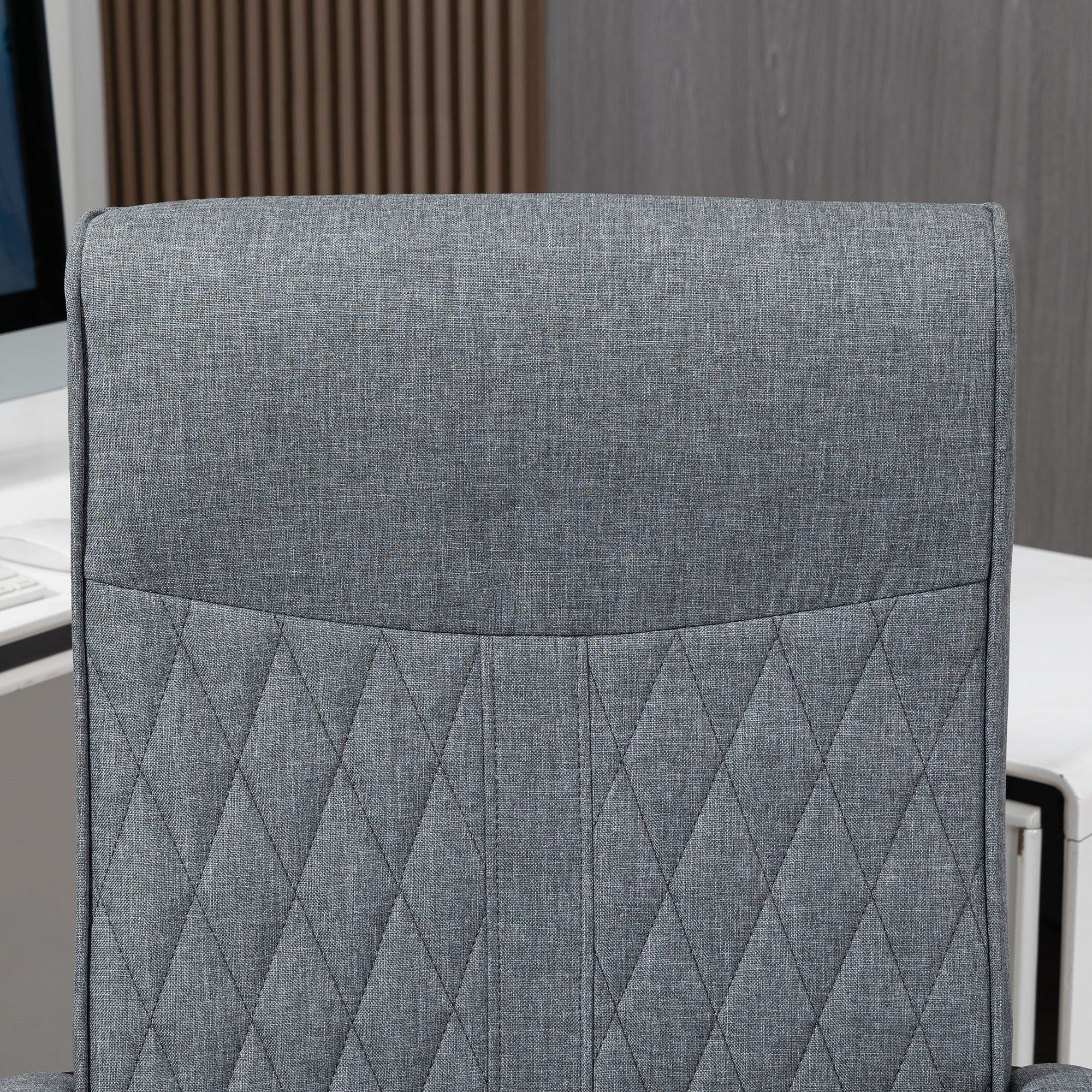 Primer plano de la parte trasera de la silla de oficina gris. Presenta un patrón de diamantes.