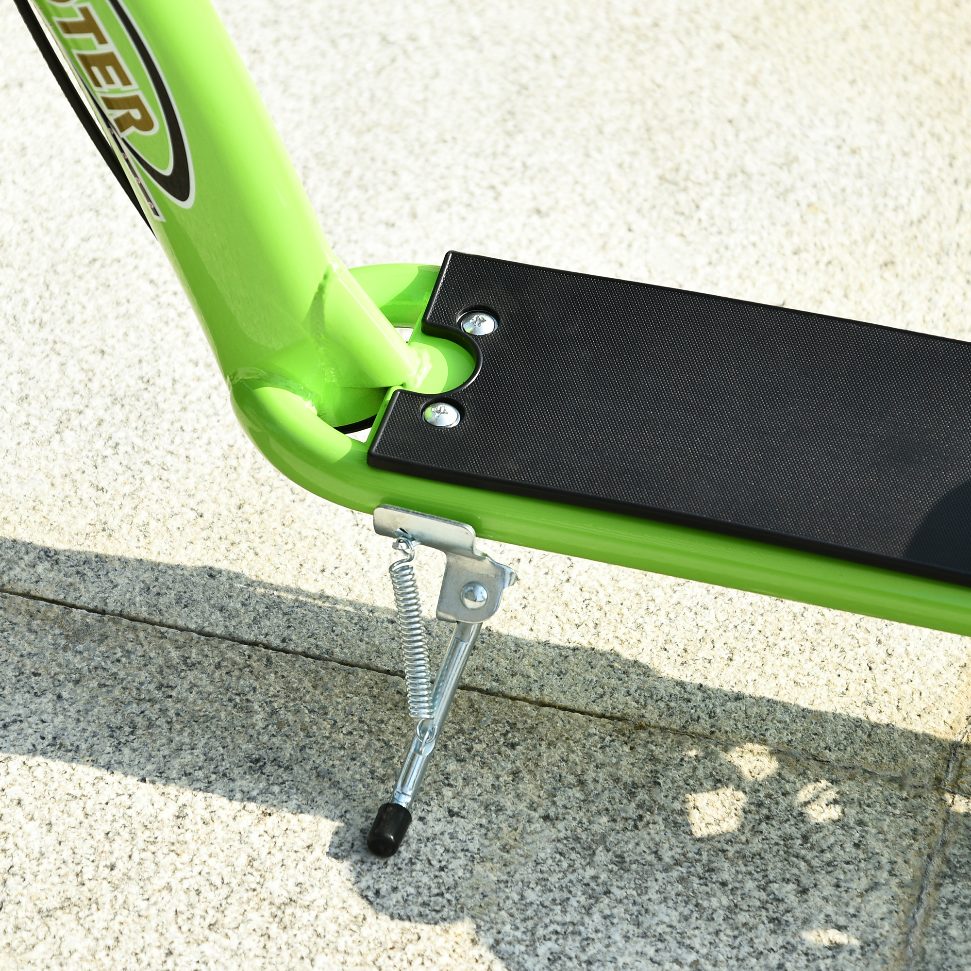 Primer plano de la base de patinete verde con superficie antideslizante negra y caballete. Fondo de piedra.