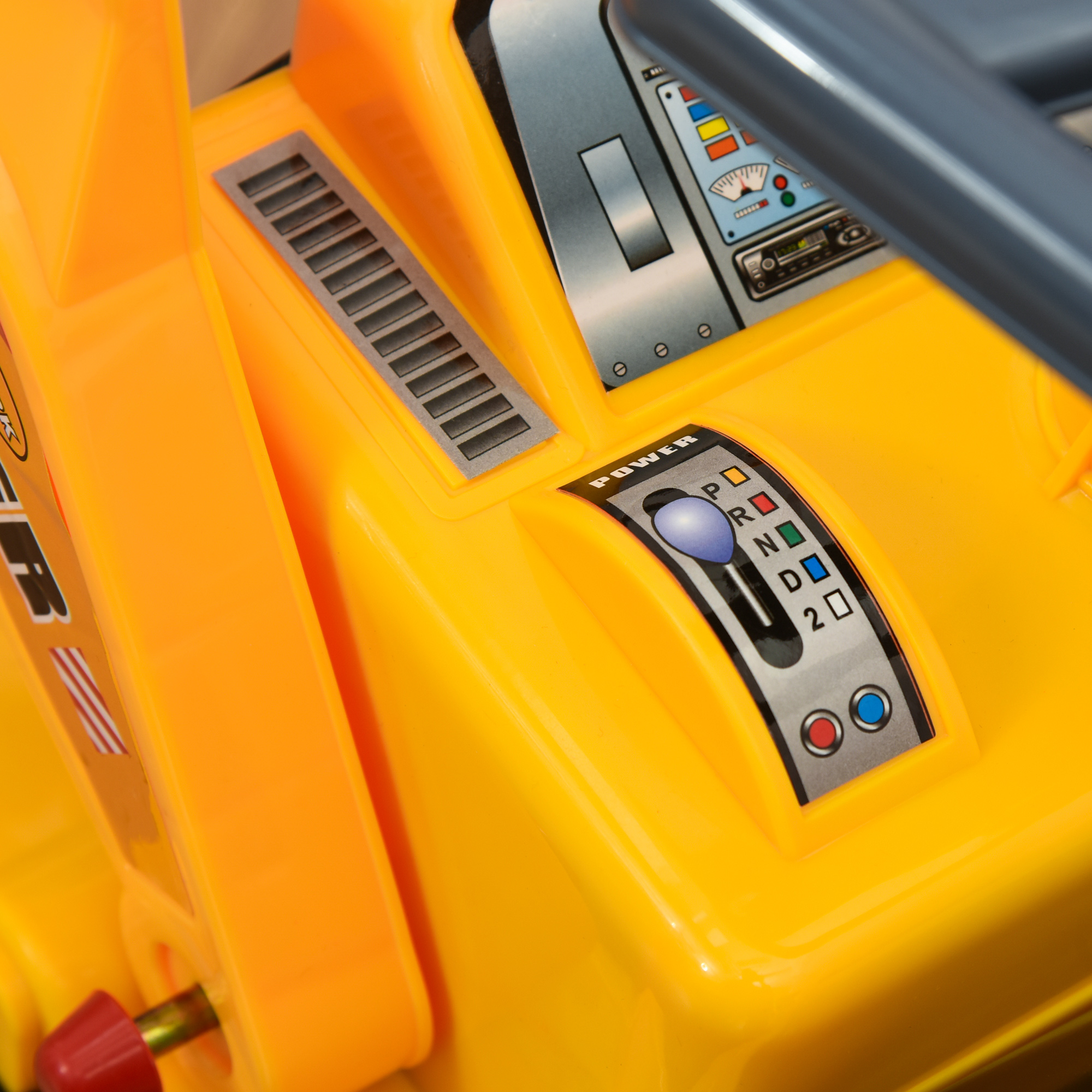 Primer plano del panel de control de un vehículo de juguete amarillo. Muestra selector de marchas e interruptor de encendido.