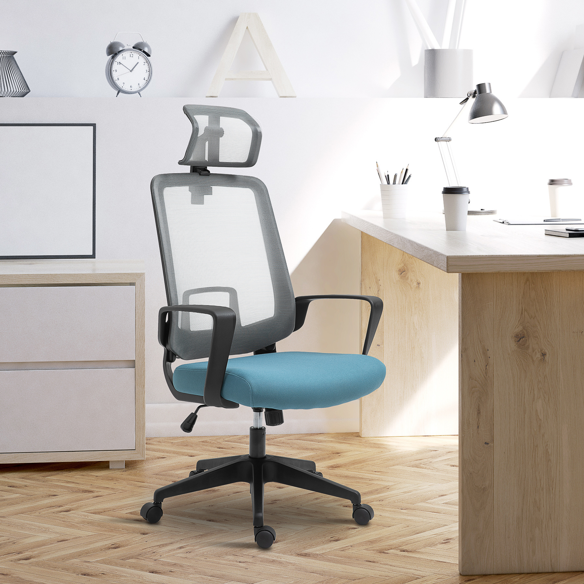 Una silla de oficina con respaldo de malla gris y asiento azul, frente a un escritorio con lámpara.