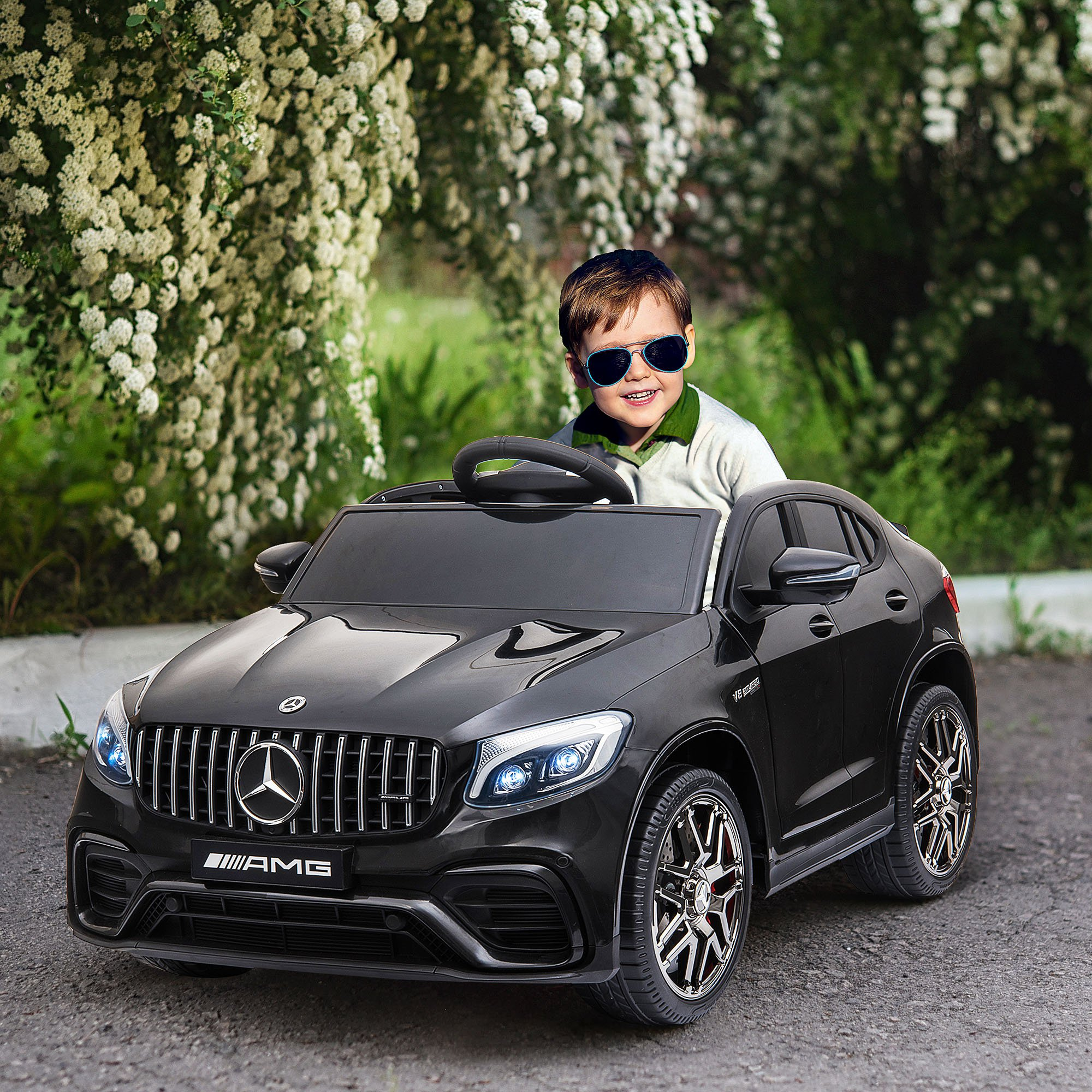 Un ragazzo con gli occhiali da sole guida un'auto giocattolo nera.