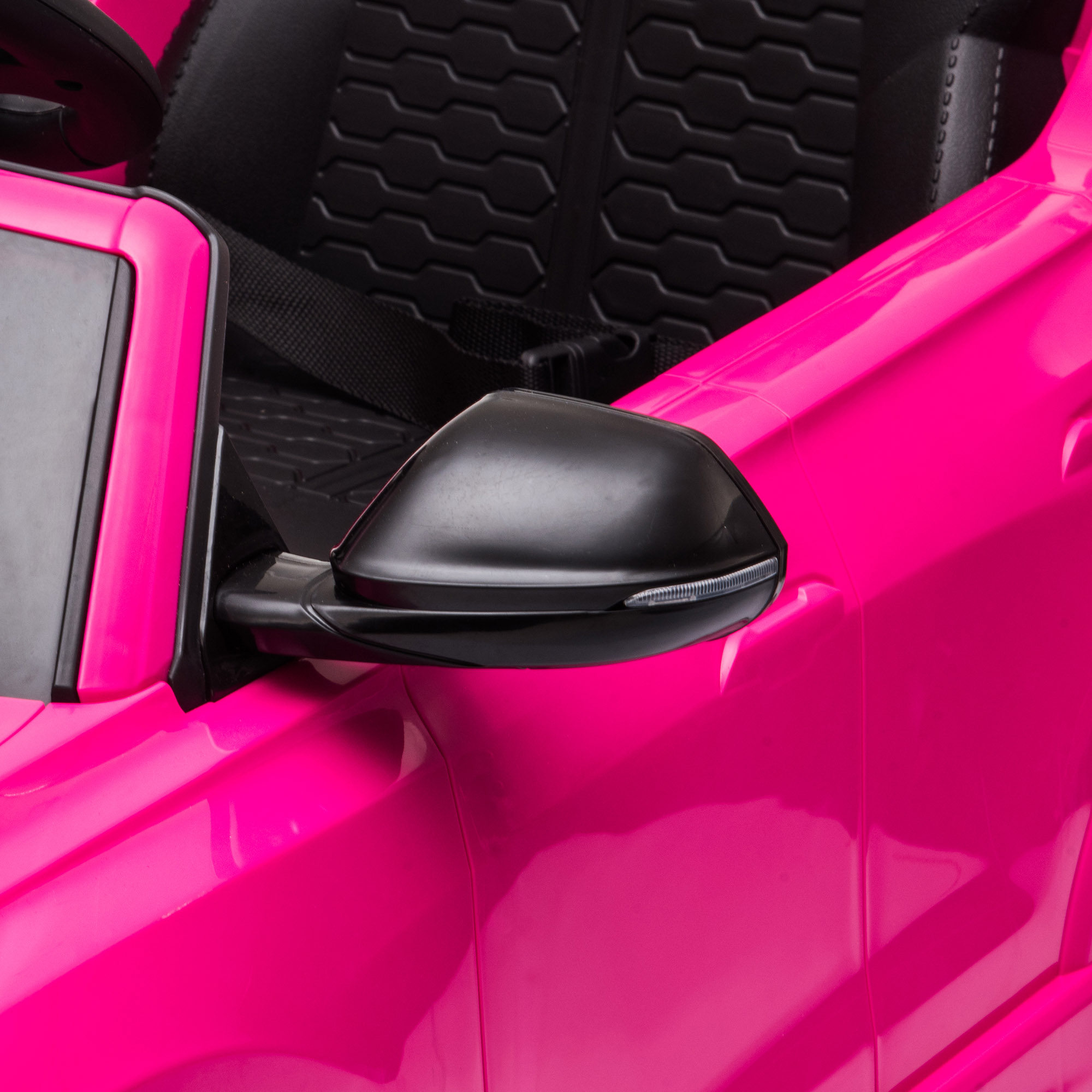Primer plano del espejo lateral de un coche de juguete rosa, mostrando su carcasa negra y diseño elegante.