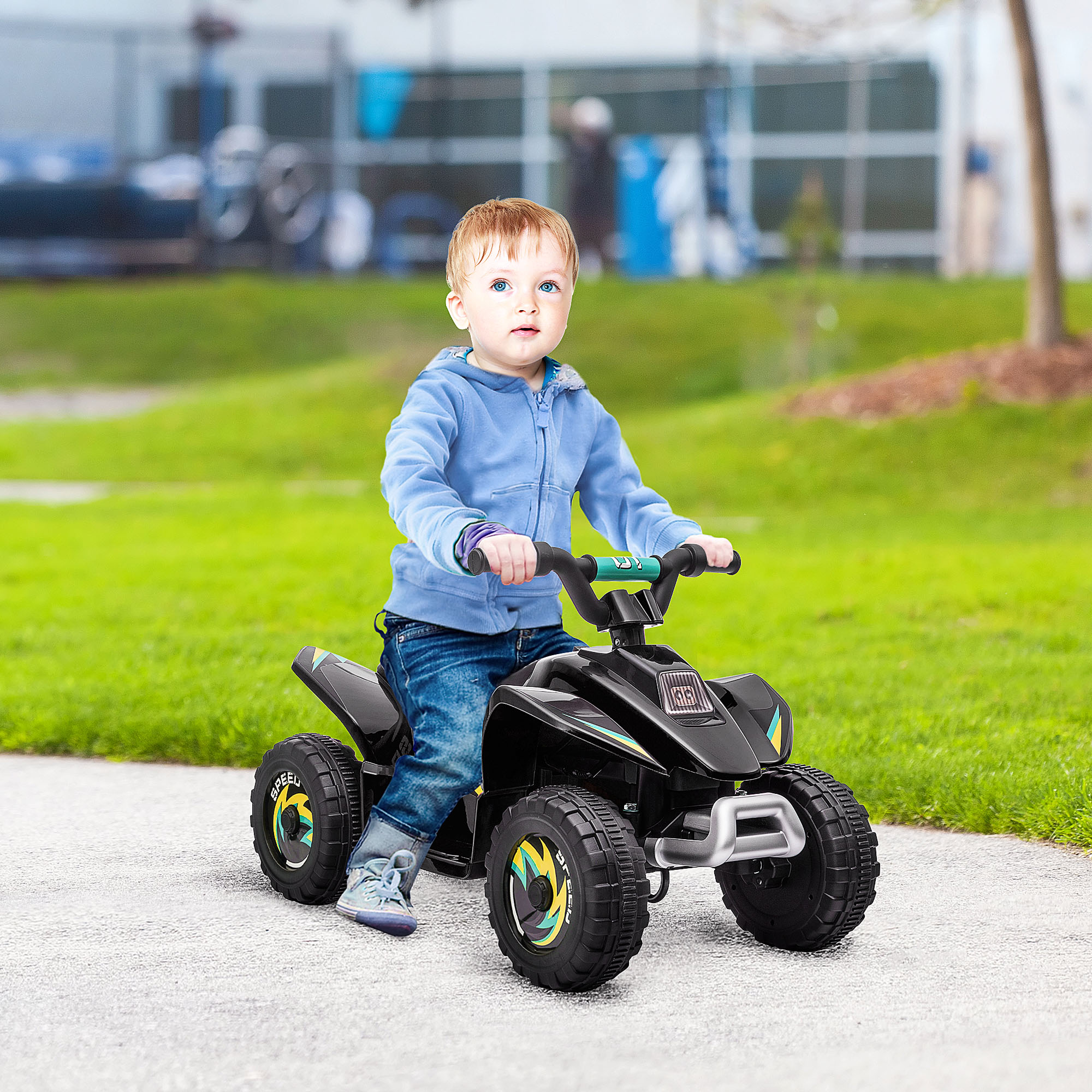 Un ragazzino che guida un giocattolo ATV nero su un sentiero lastricato. Indossa una giacca blu.