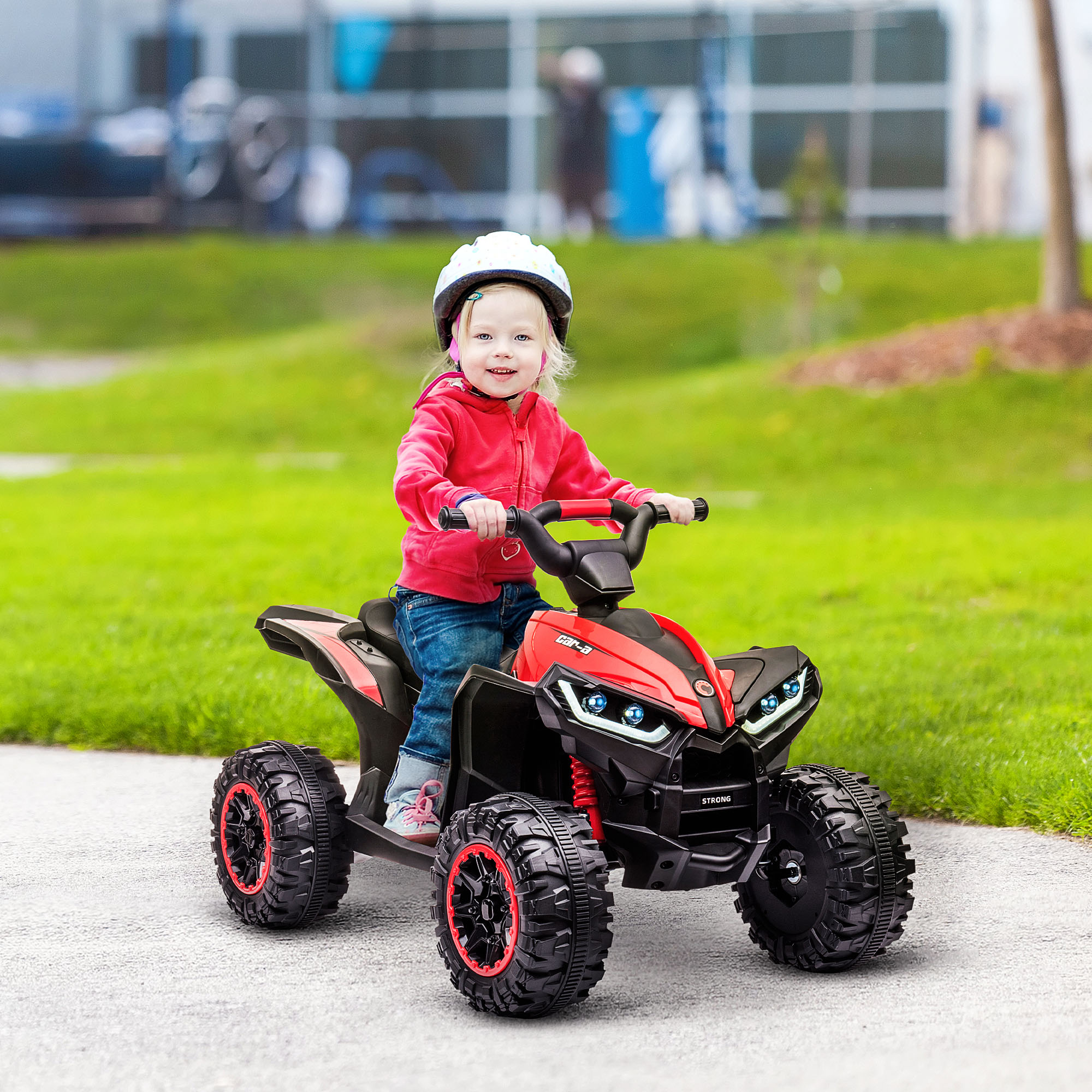Un bambino piccolo guida un quad rosso e nero in un'area erbosa. Il bambino indossa un casco.