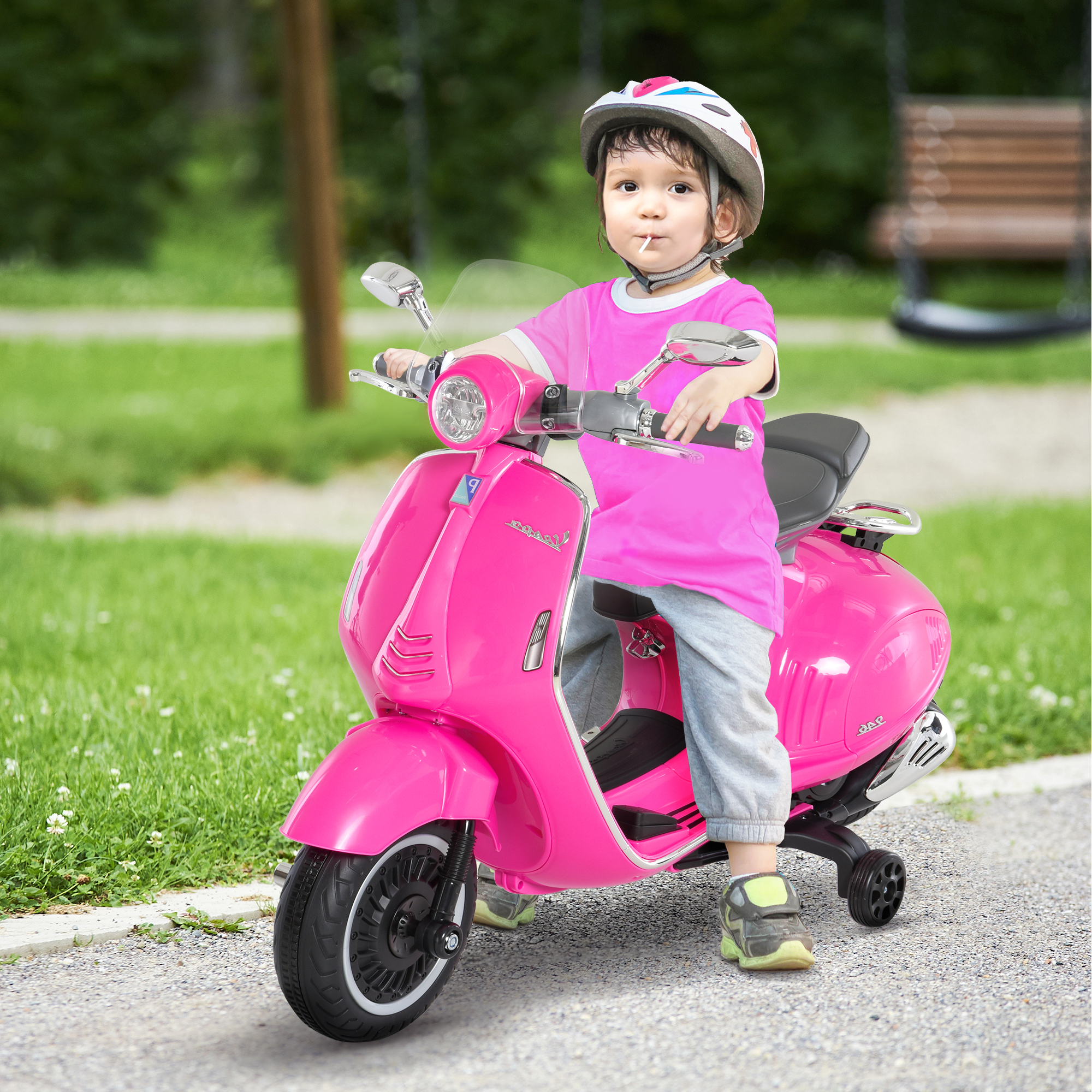 Un bambino su un giocattolo scooter rosa, casco, su un sentiero pavimentato.