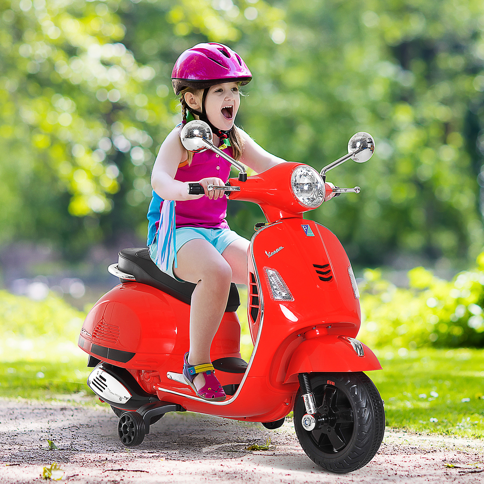Una niña montando un scooter Vespa de juguete rojo en un camino en un parque.