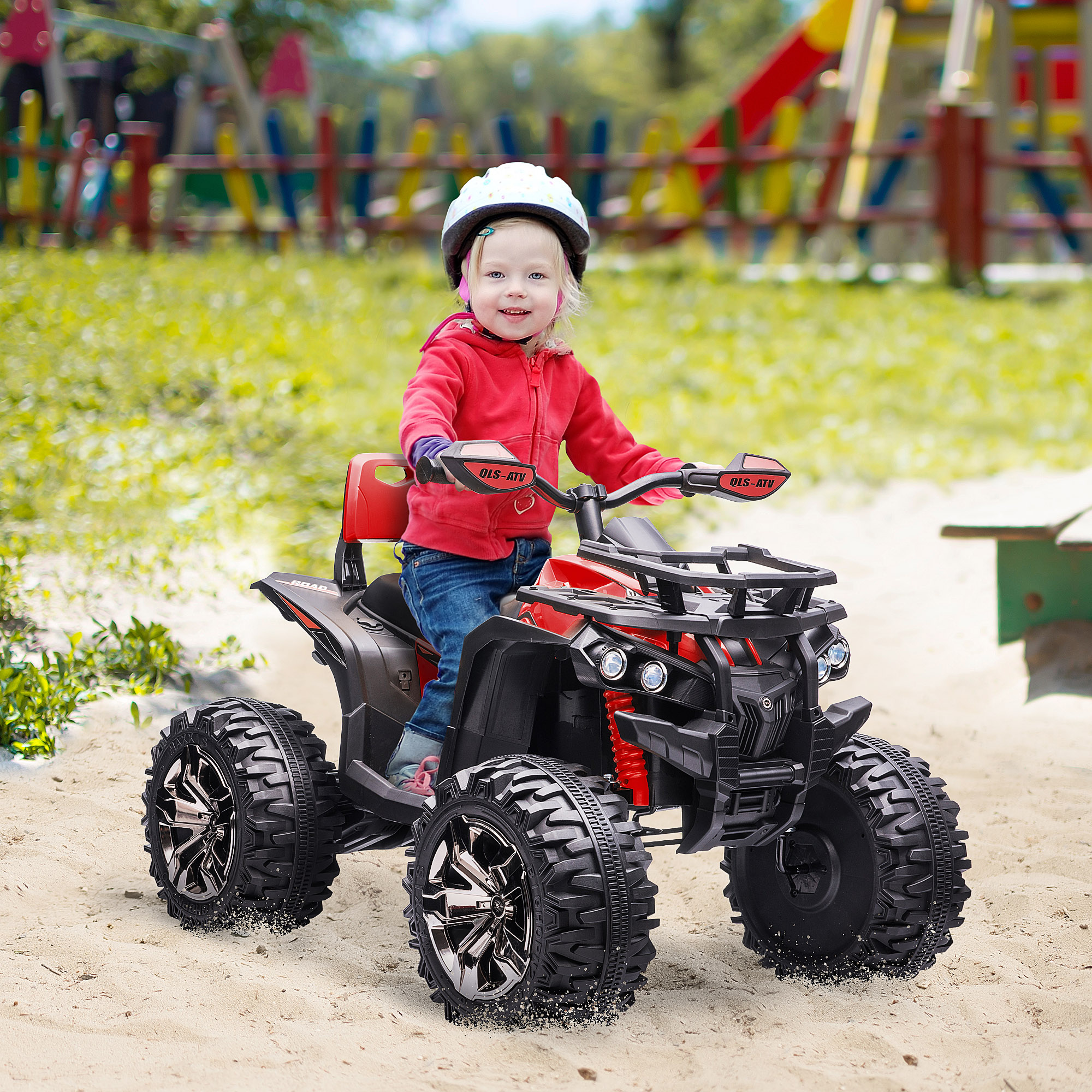 Un bambino con una giacca rossa guida un quad giocattolo rosso e nero sulla sabbia. Il quad ha pneumatici grandi.