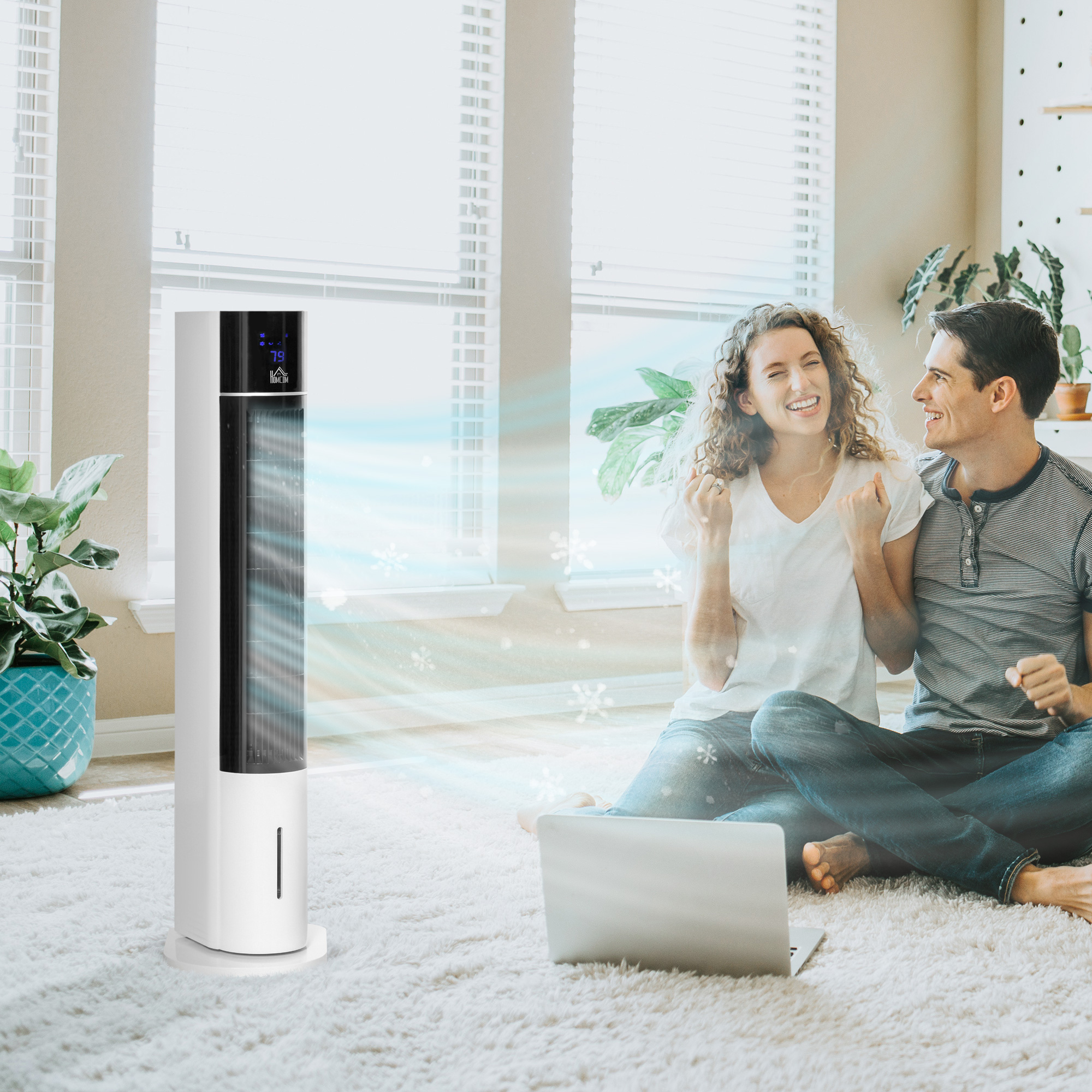 Una pareja en una habitación con un ventilador de torre blanco. Sonríen, el ventilador sopla aire.