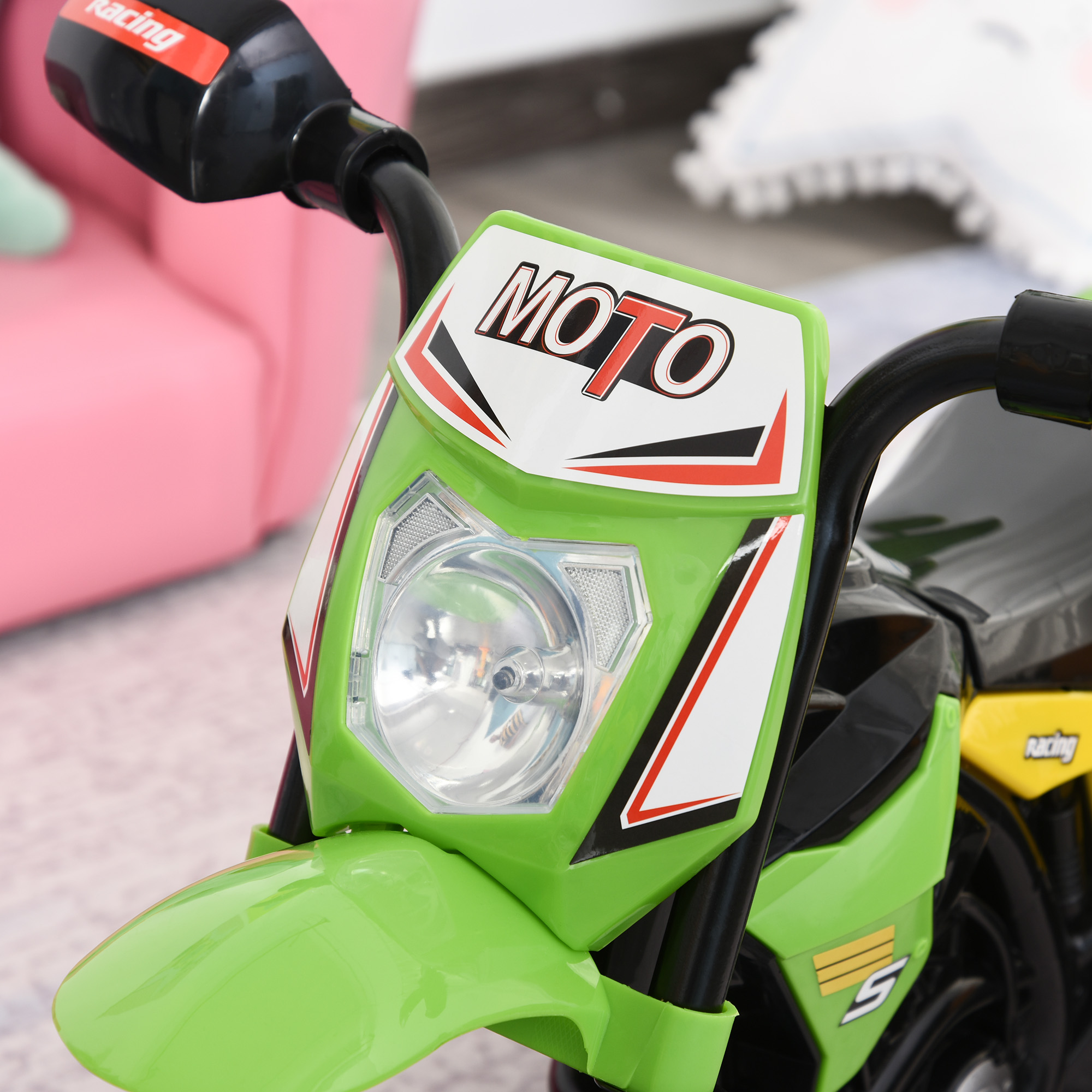 Primer plano de la parte delantera de una moto de juguete verde. Muestra el faro y la palabra 'MOTO'.