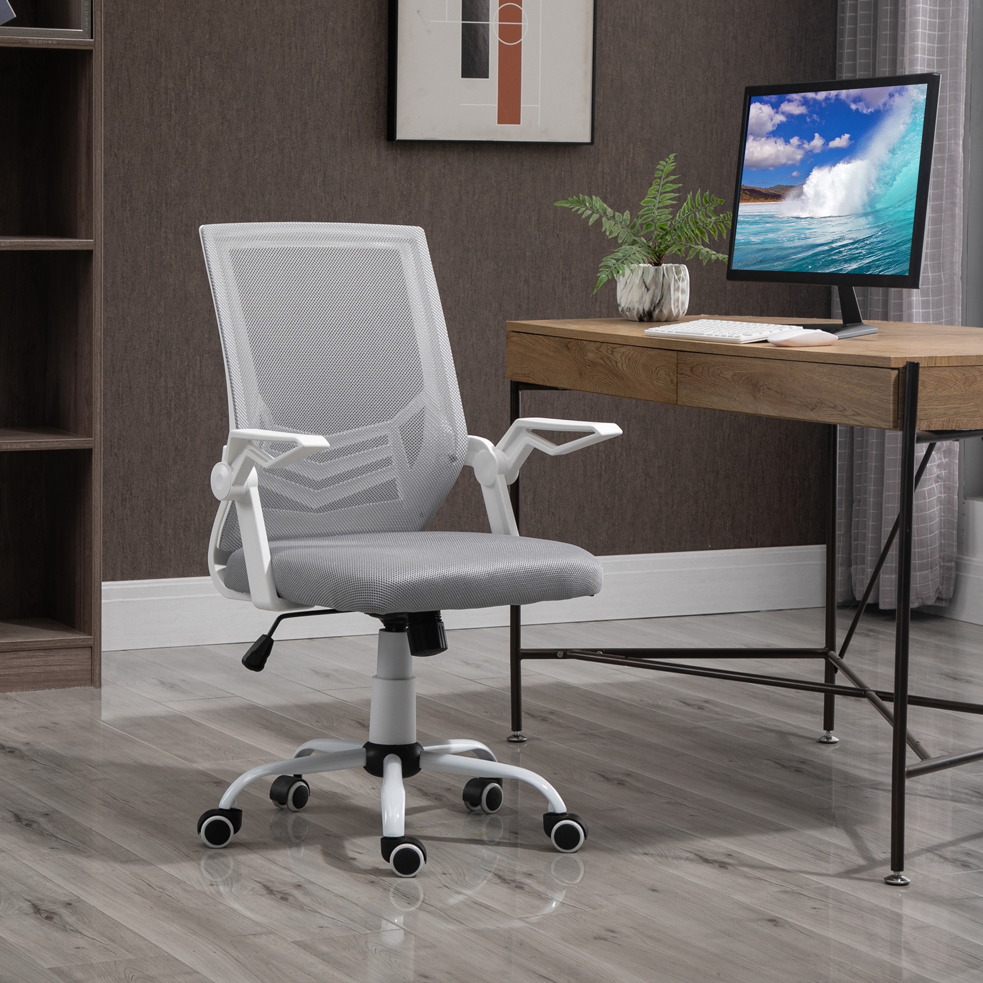 Una oficina con una silla blanca con respaldo de malla. Hay un escritorio de madera, un ordenador y una estantería.