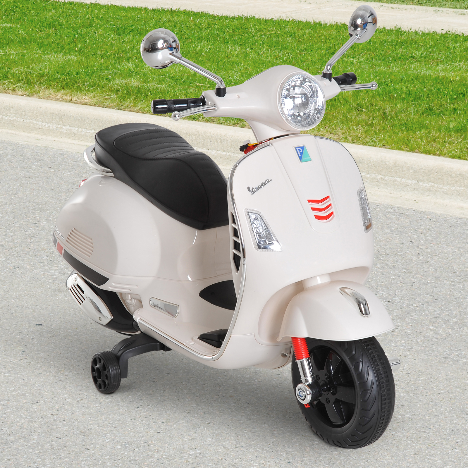 Scooter Vespa de juguete color crema con ruedas negras y fondo de césped verde.