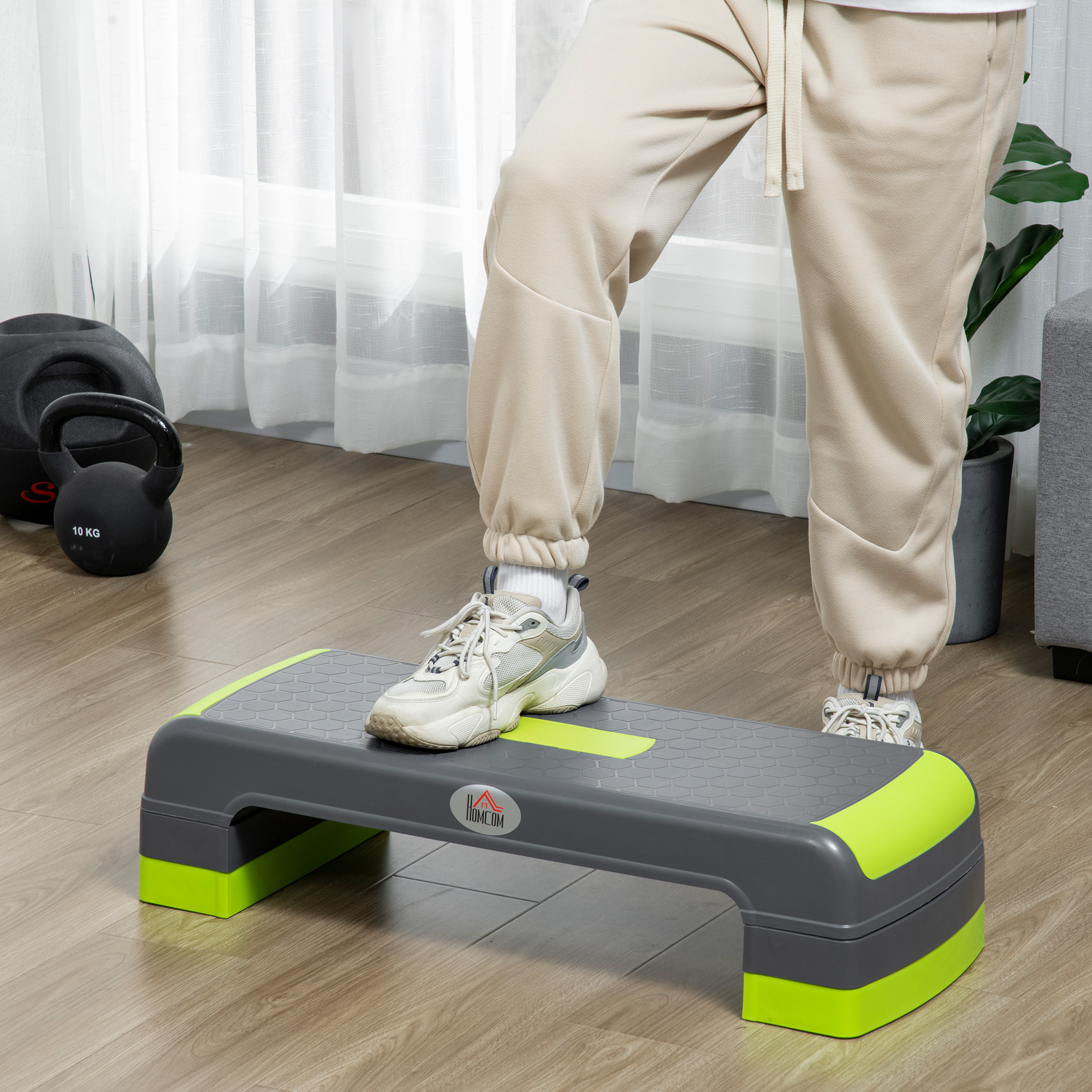 Una persona in piedi su una piattaforma a gradini grigia e verde all'interno, con pesi visibili sullo sfondo.