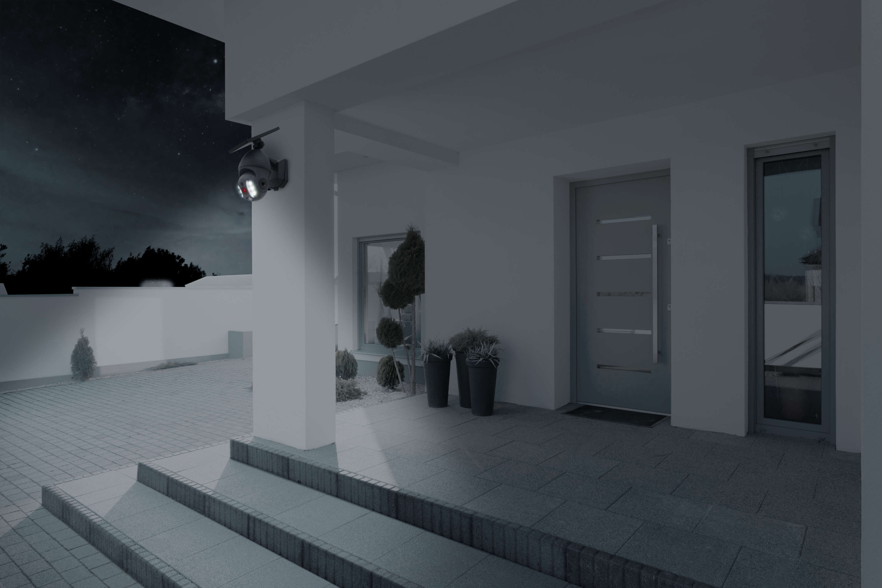 Außenansicht eines Hauses bei Nacht mit einer Überwachungskamera.