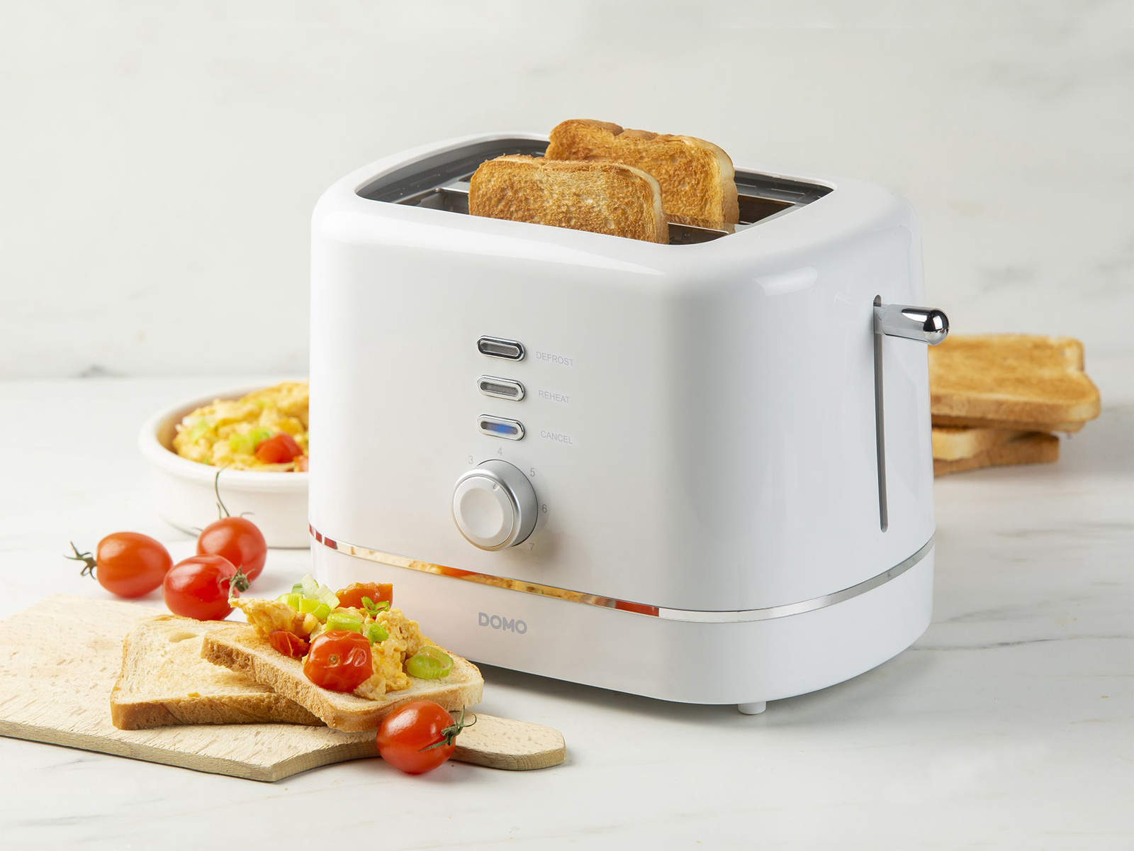 Un tostapane bianco con due fette di pane tostato e un piatto di cibo con pomodori e pane.