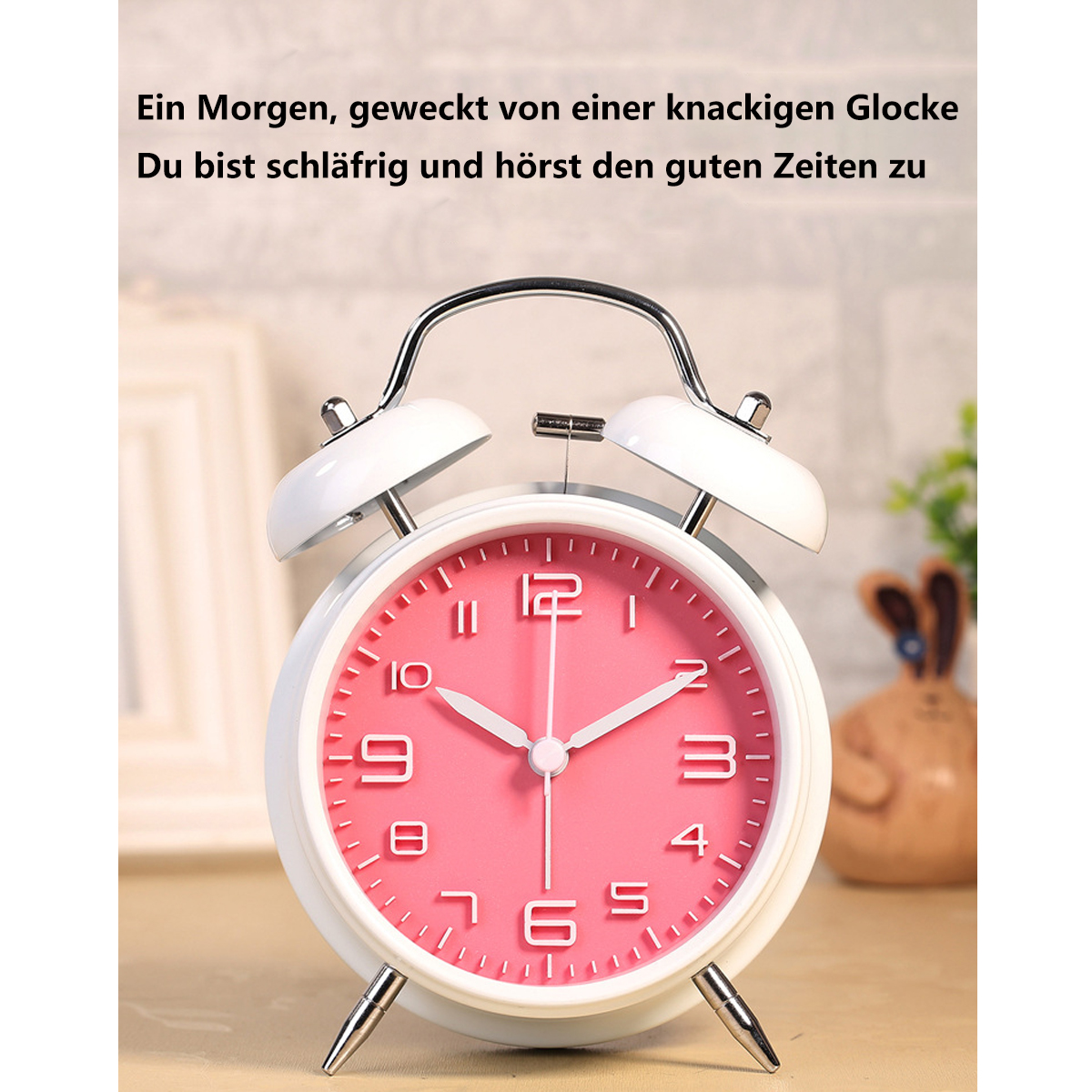 Ein rosafarbener Wecker mit weißen Glocken und Zahlen steht auf Holz.
