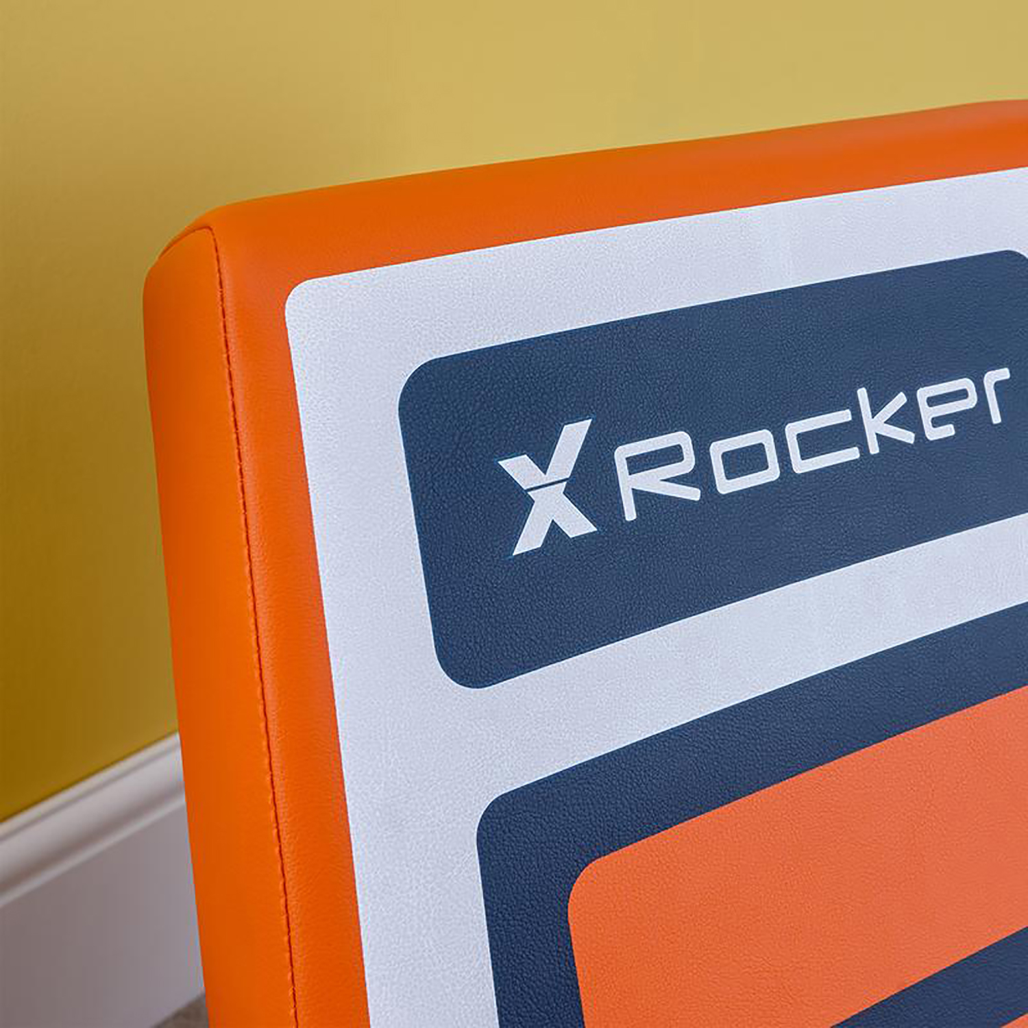 Nahaufnahme des Logos von XRockers in Weiß und Orange auf einem Gaming-Stuhl.