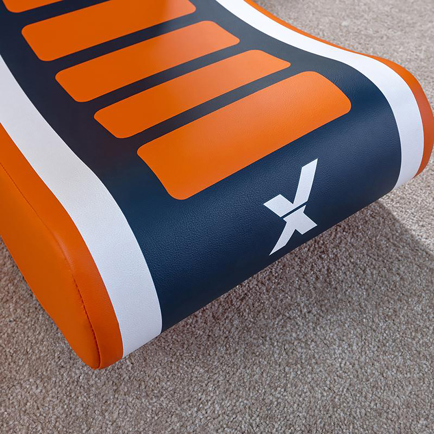 Nahaufnahme eines Stuhls mit orangefarbenen und weißen Linien. Der Stuhl steht auf einem Teppich. Dunkelblauer Hintergrund.