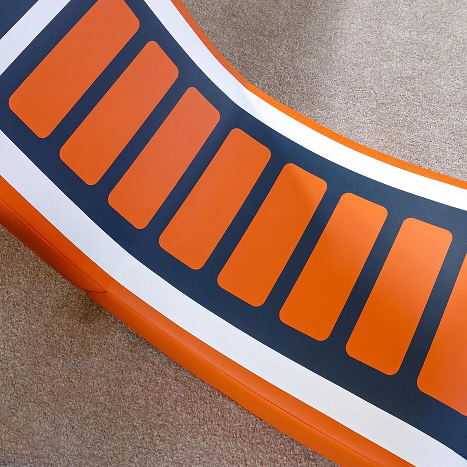 Eine orangefarbene und blaue aufblasbare Matte mit weißen Streifen, die auf einer beigen Oberfläche liegt.