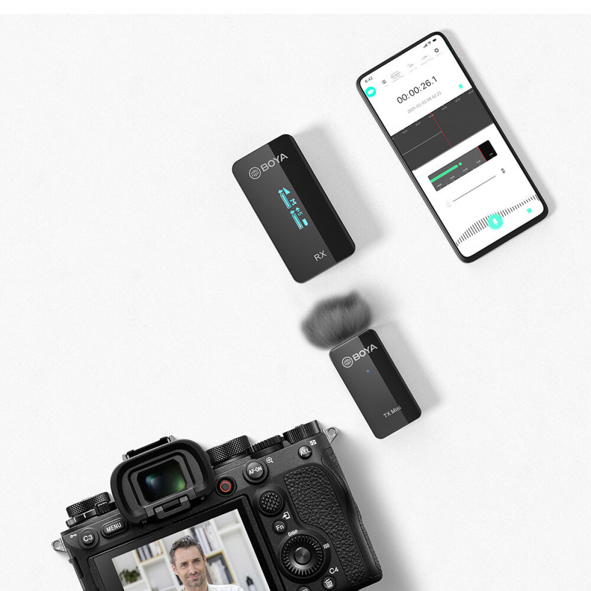 Eine Kamera, ein Mikrofon und ein Smartphone sind auf einer weißen Oberfläche angeordnet. Das Telefon zeigt Daten an.