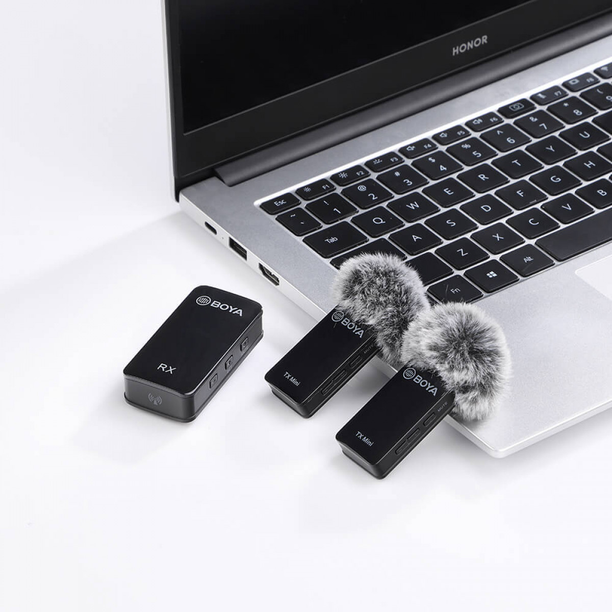 Un laptop con due piccoli microfoni e un ricevitore, tutto nero, su una superficie bianca.