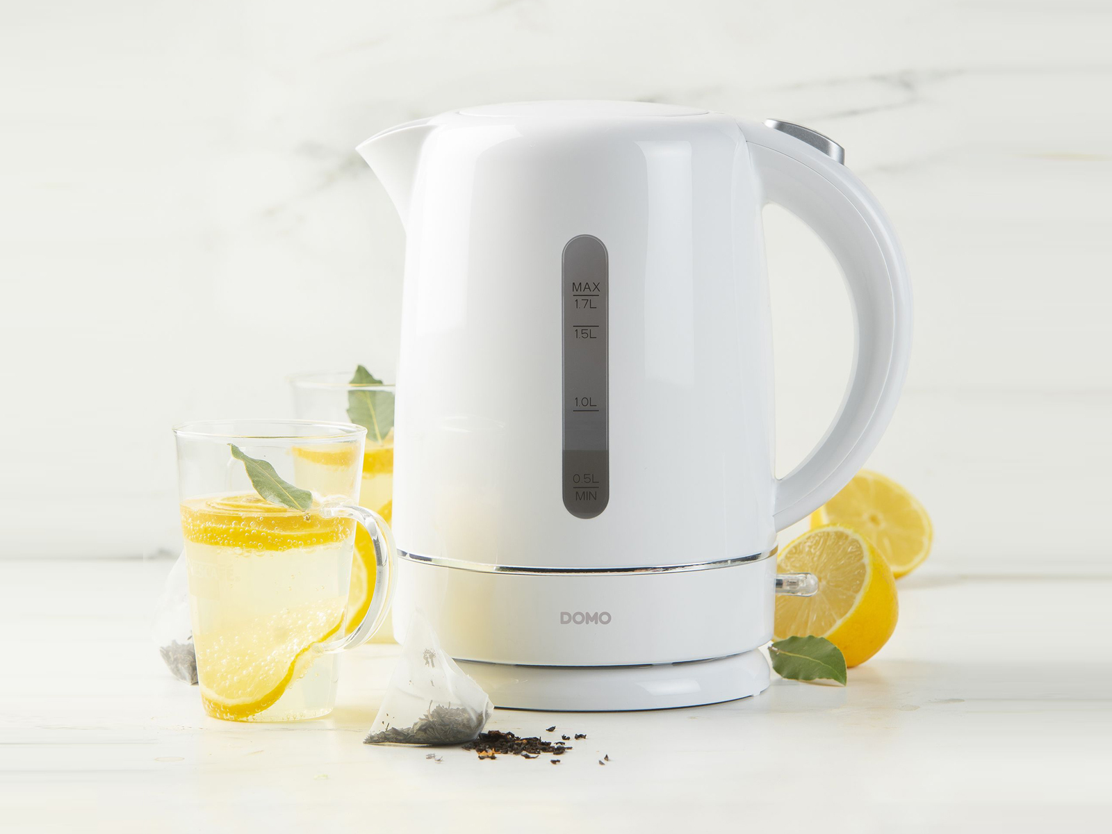 Biały czajnik elektryczny ze wskaźnikiem poziomu wody, dwie szklanki z lemoniadą i cytryny.