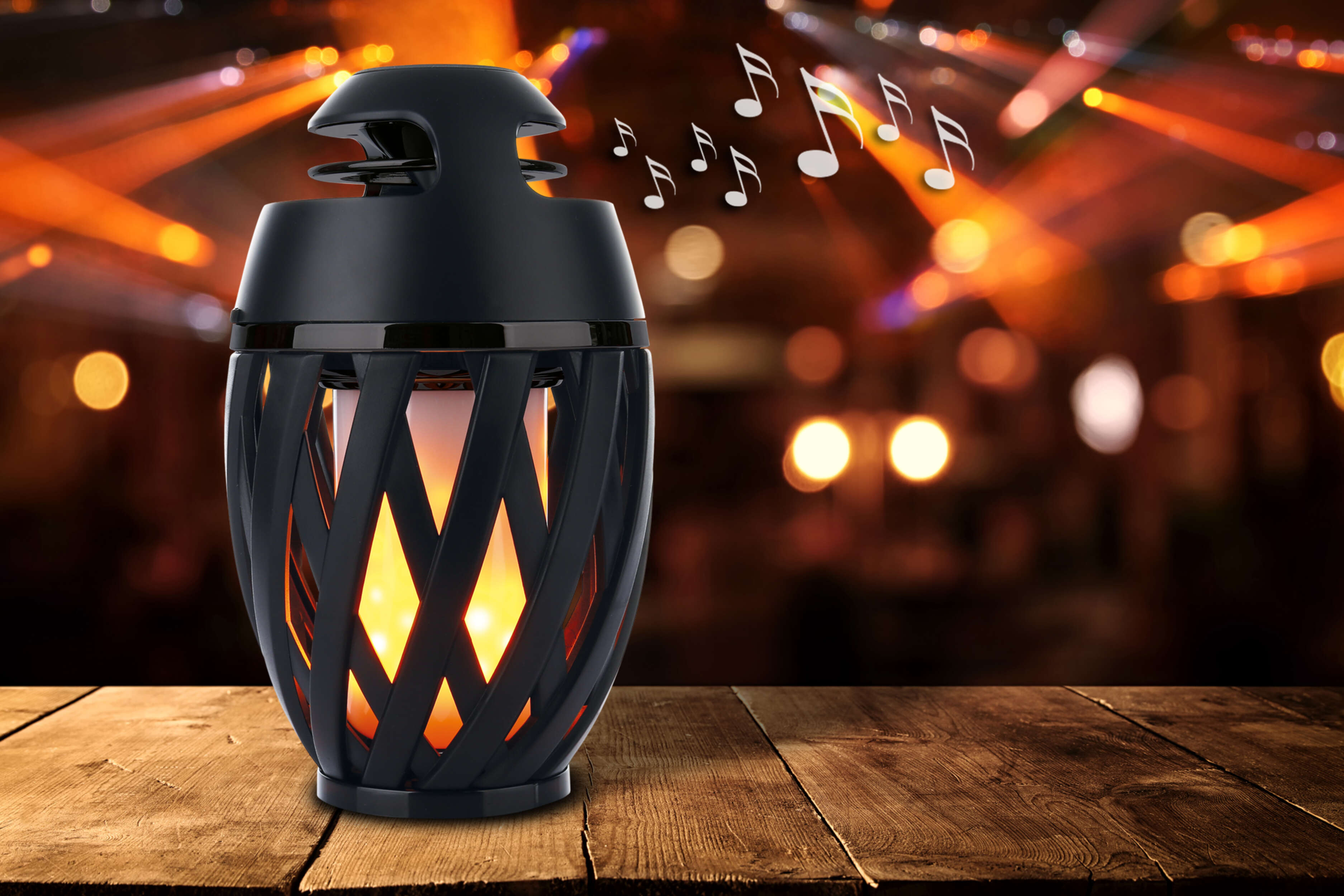 Ein schwarzer Lautsprecher mit einem flammenartigen Lichteffekt, auf einem Holztisch mit verschwommenem Hintergrund.
