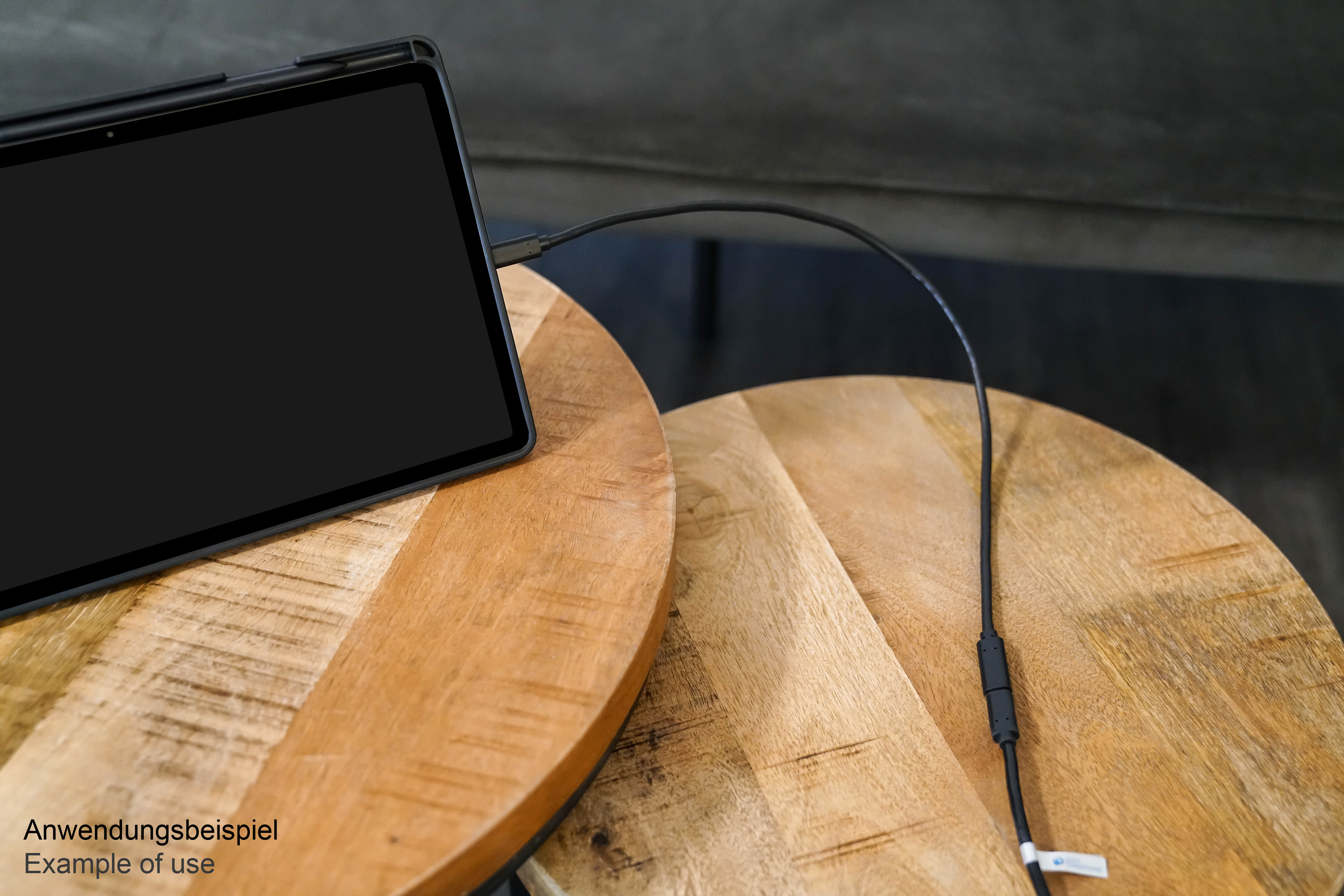 Tablet collegato a un cavo su tavoli di legno. Testo di esempio di utilizzo visibile.