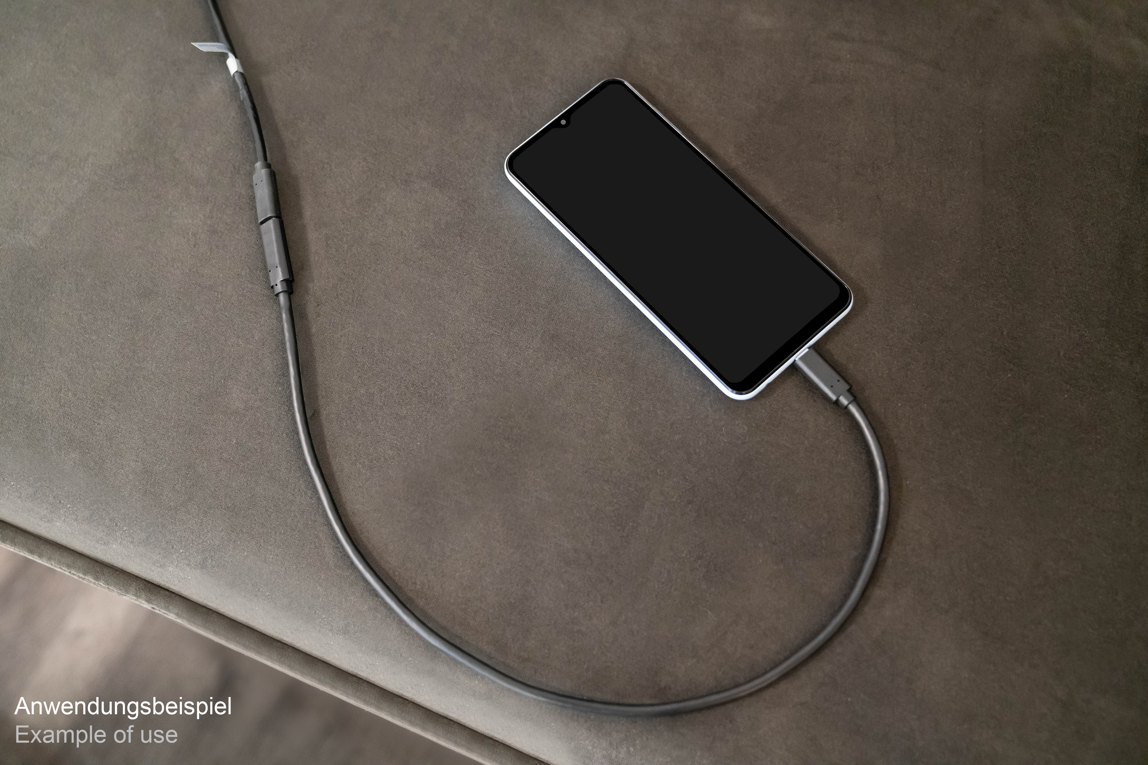 Ein Telefon, das auf einer braunen Oberfläche geladen wird. Ein Ladekabel ist mit dem Telefon verbunden.