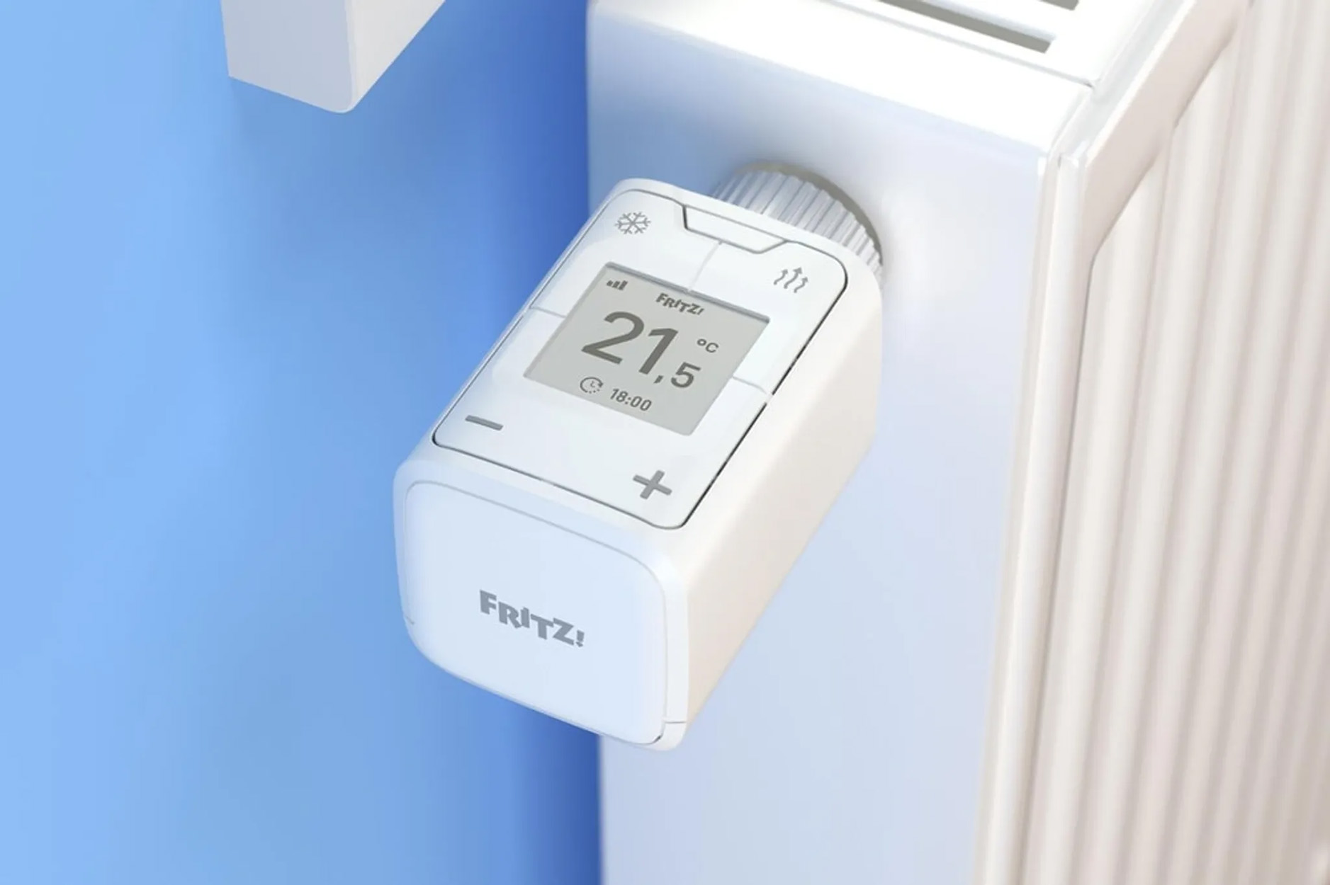 Weißer Smart-Thermostat an einem Heizkörper, der Temperatur und Uhrzeit anzeigt. Blaue Wand im Hintergrund.
