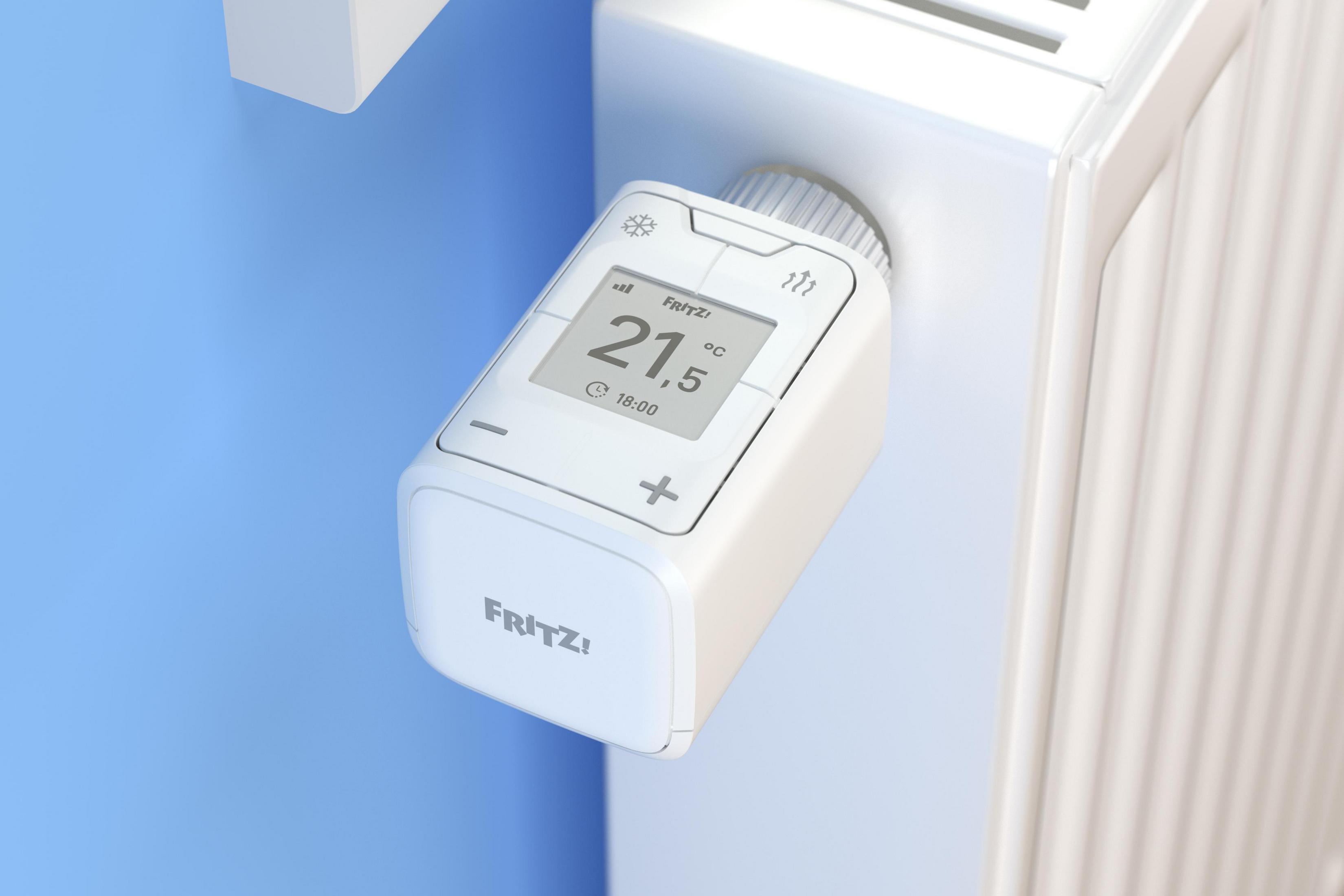 Weißes Thermostat an einem weißen Heizkörper mit einer blauen Wand. Anzeige zeigt 21,5 Grad.