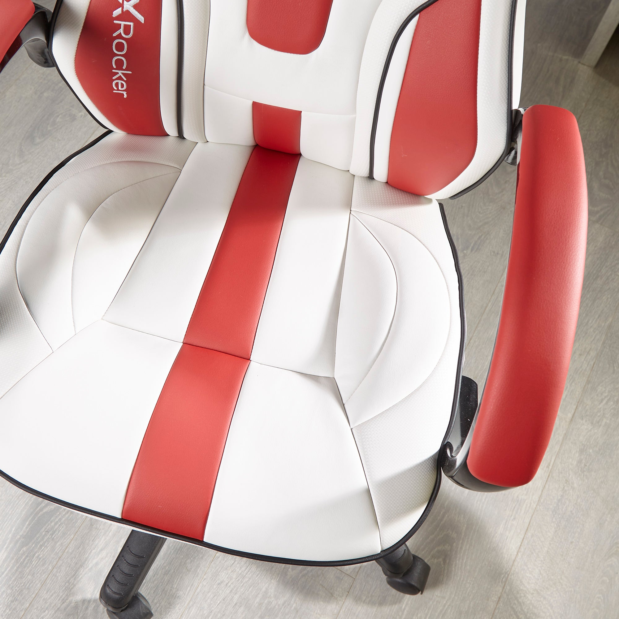 Nahaufnahme eines weißen und roten Gaming-Stuhlsitzes. Sichtbar sind Sitz, Rückenlehne, Armlehnen und schwarzes Gestell mit Rädern.