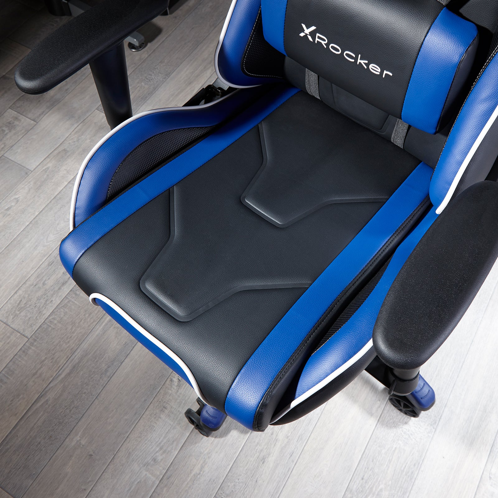 Blau-schwarzer Gaming-Stuhl. Der Stuhl hat eine Kopfstütze und Armlehnen. Holzboden im Hintergrund.