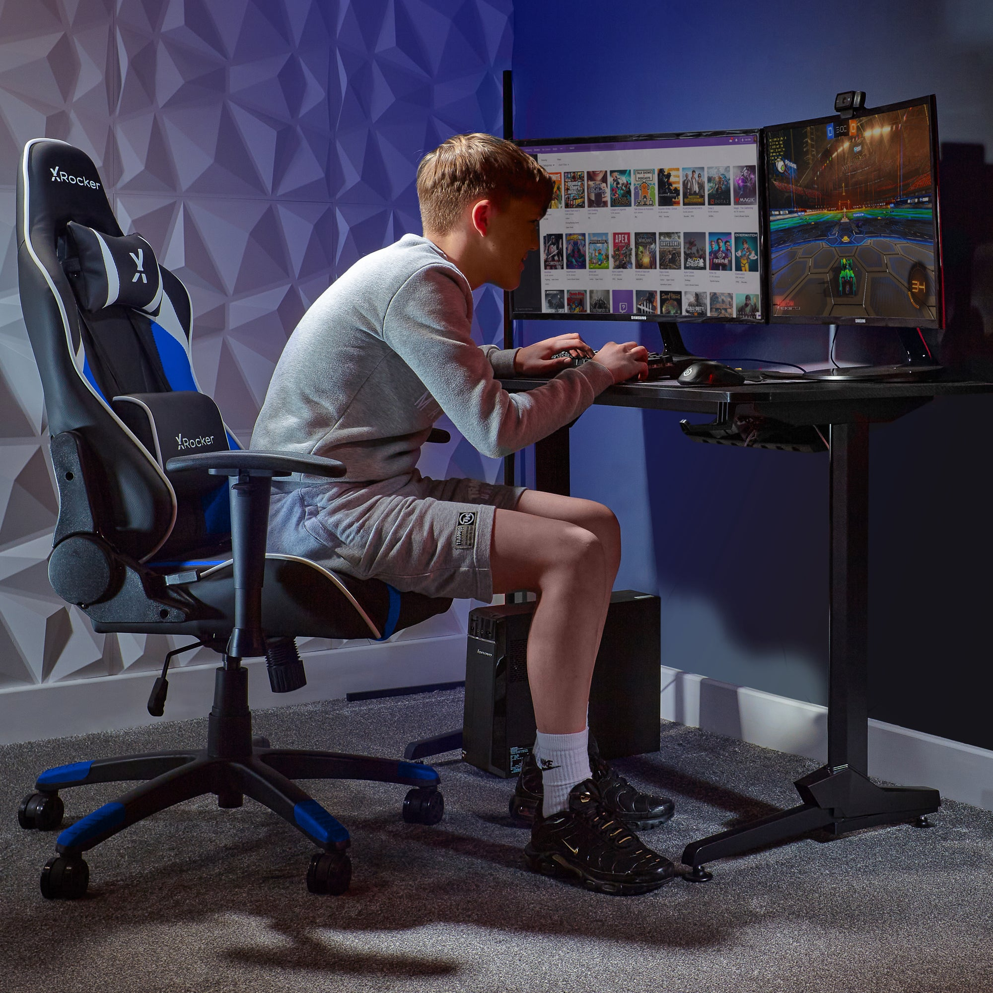 Teenager spielt Spiele auf einem Gaming-Stuhl mit zwei Monitoren und Schreibtisch.