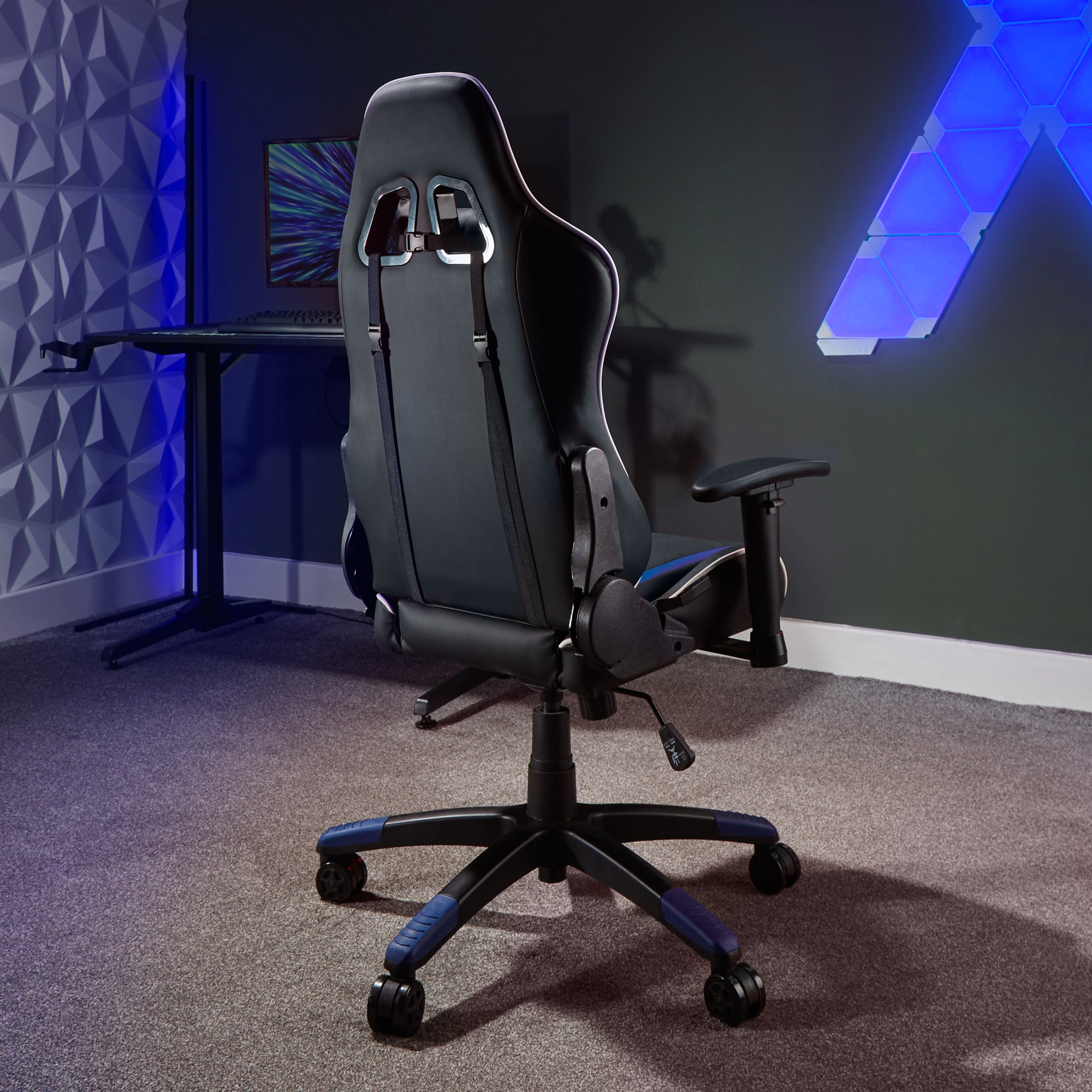 Schwarzer Gaming-Stuhl, Rückansicht. Blaue Akzente, auf grauem Teppich. Wand mit geometrischem Design und Computer.