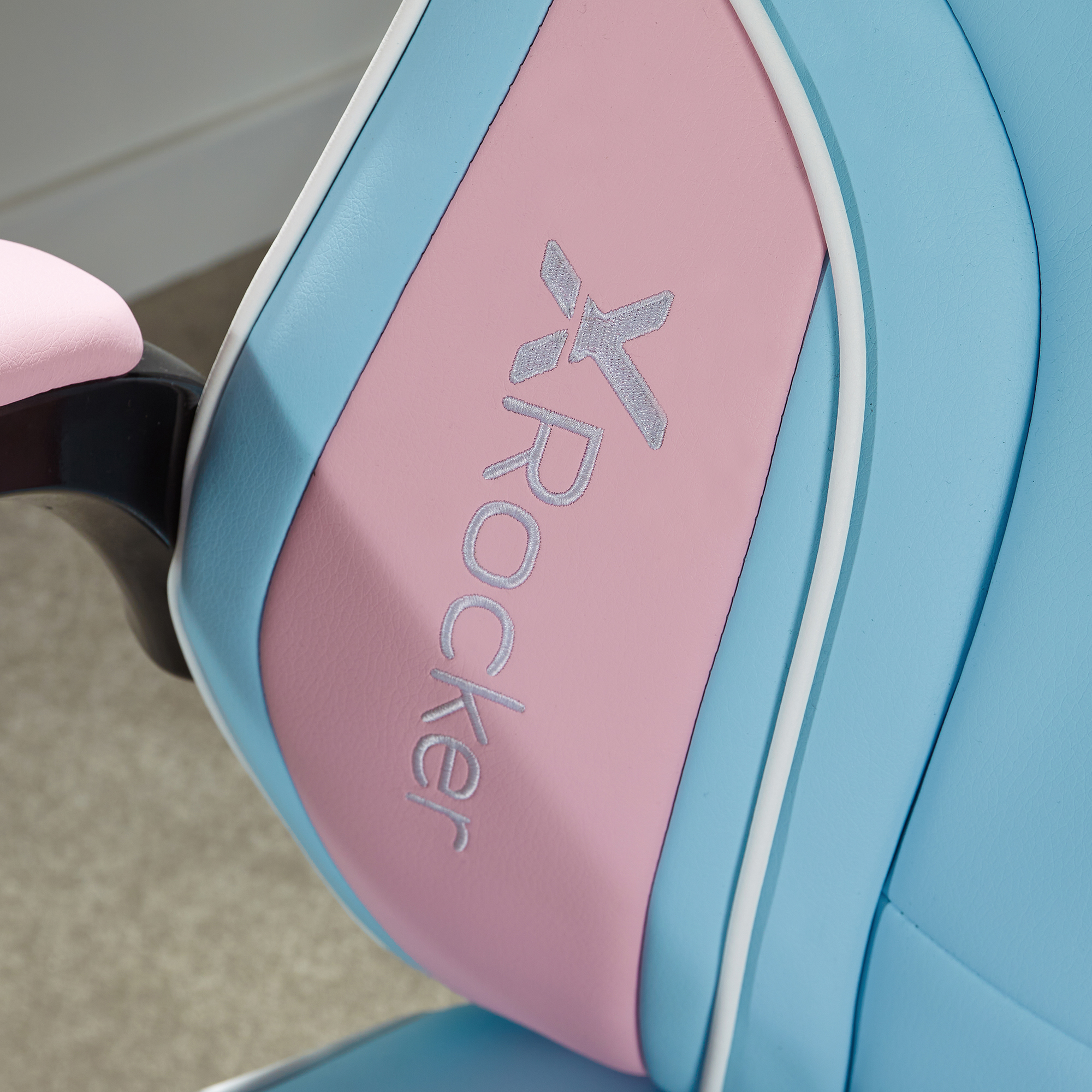 Nahaufnahme eines blau-rosa Gaming-Stuhls mit dem gestickten Wort 'XRockr'.