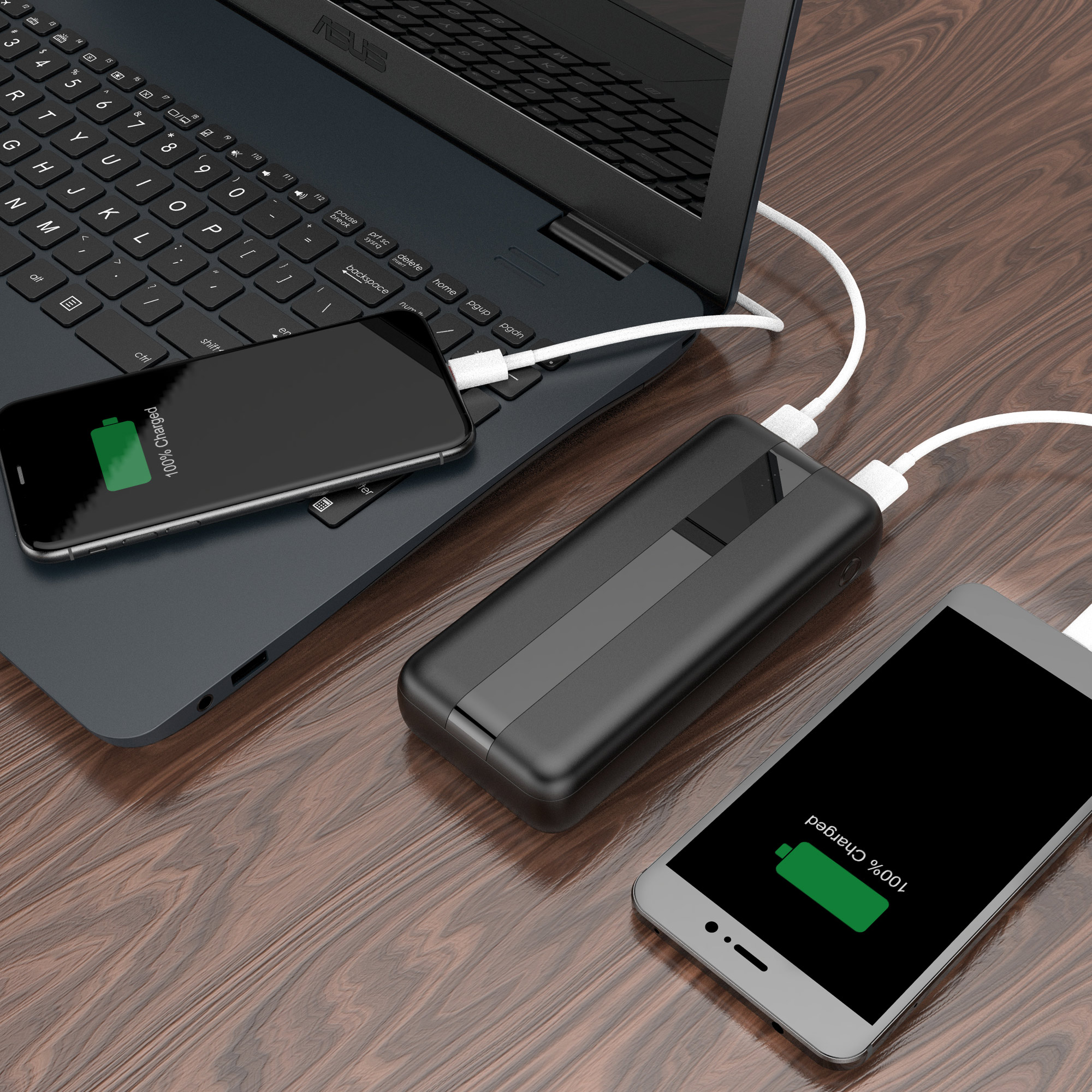 Laptop, power bank e due telefoni in carica. I telefoni mostrano 100% caricato.