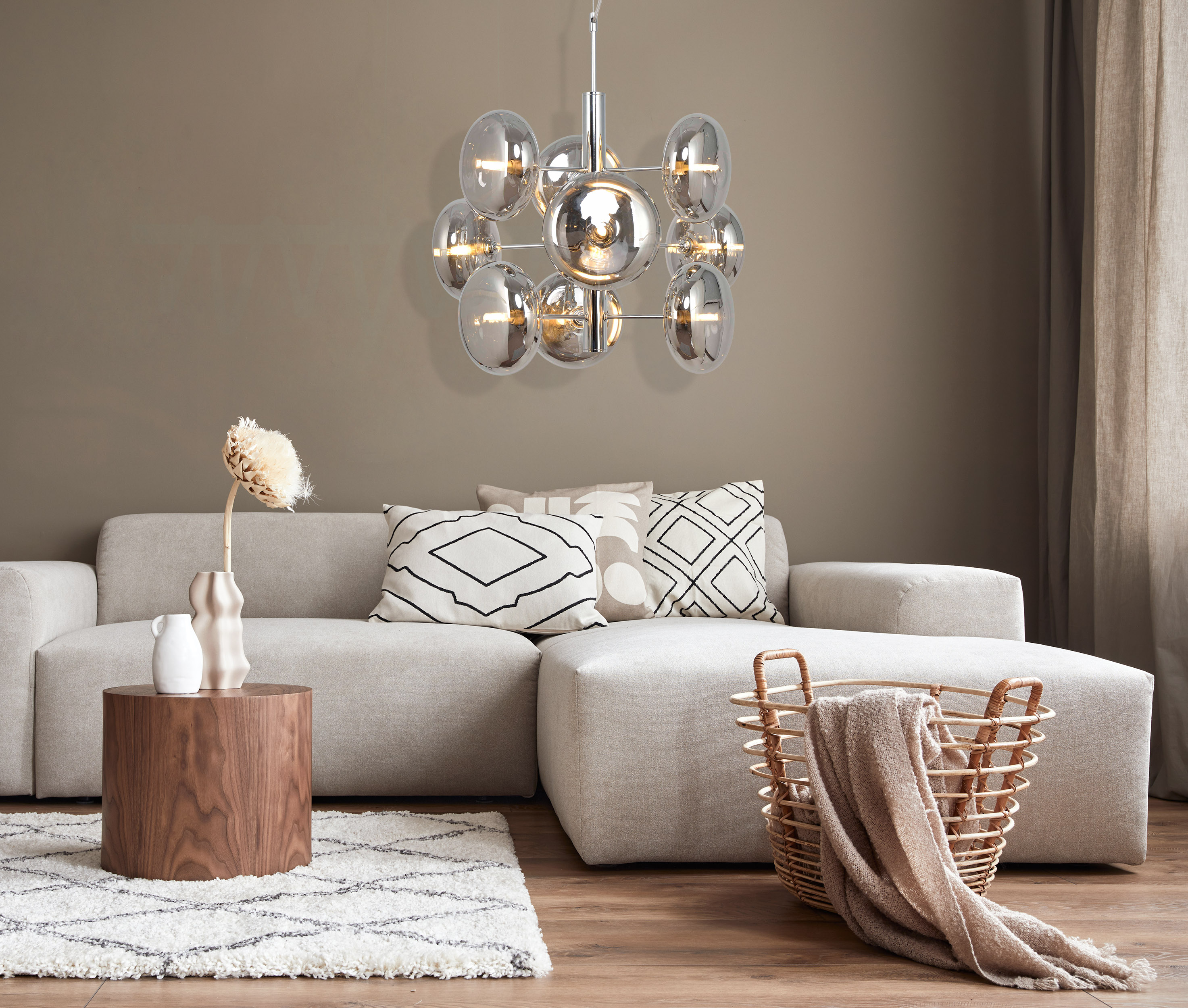 Modernes Wohnzimmer mit Sofa, Kissen, Holztisch, Teppich und Kronleuchter.