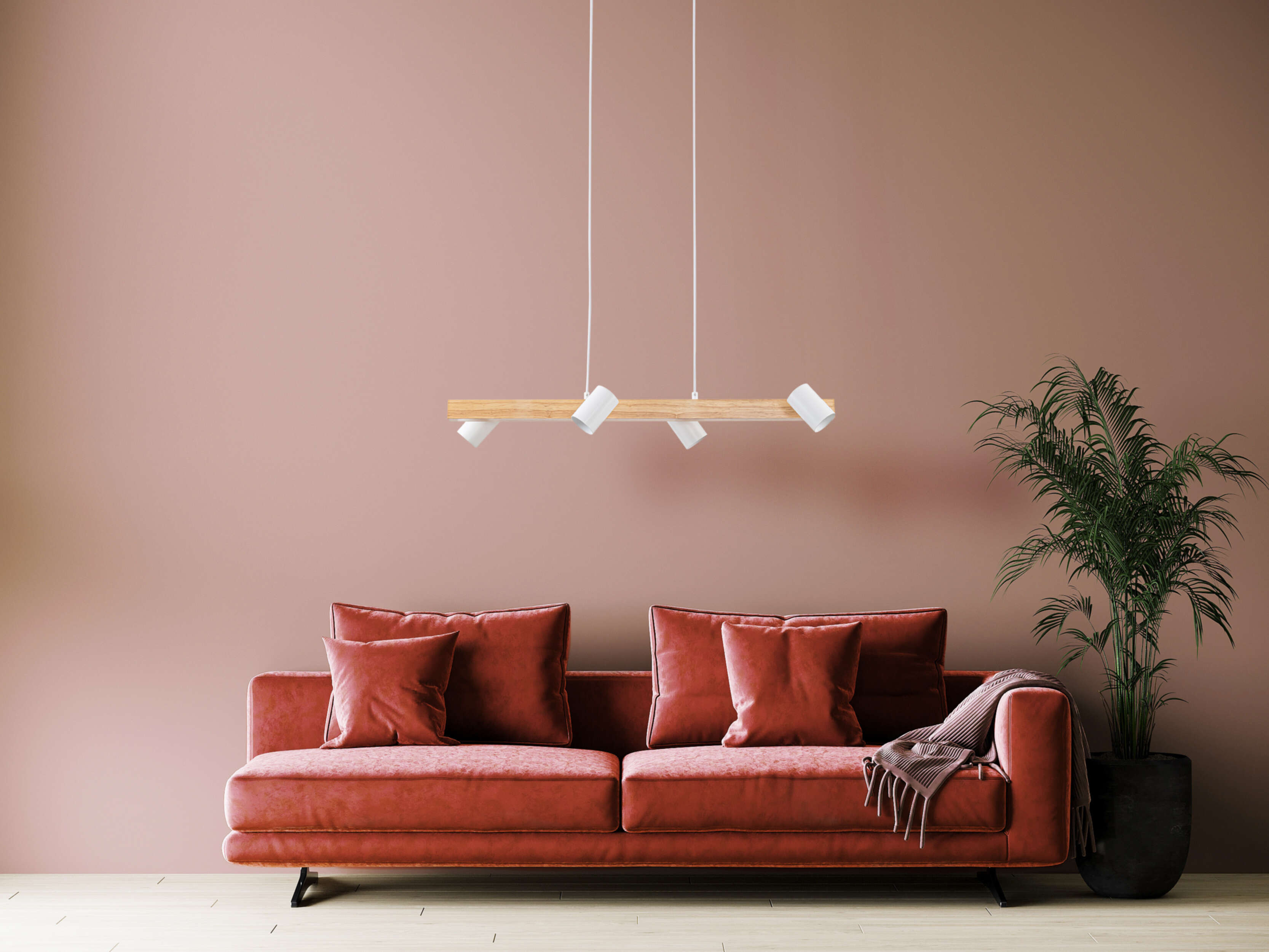 Wohnzimmer mit rotem Sofa, Kissen und einer Hängeleuchte. Rosa Wand.