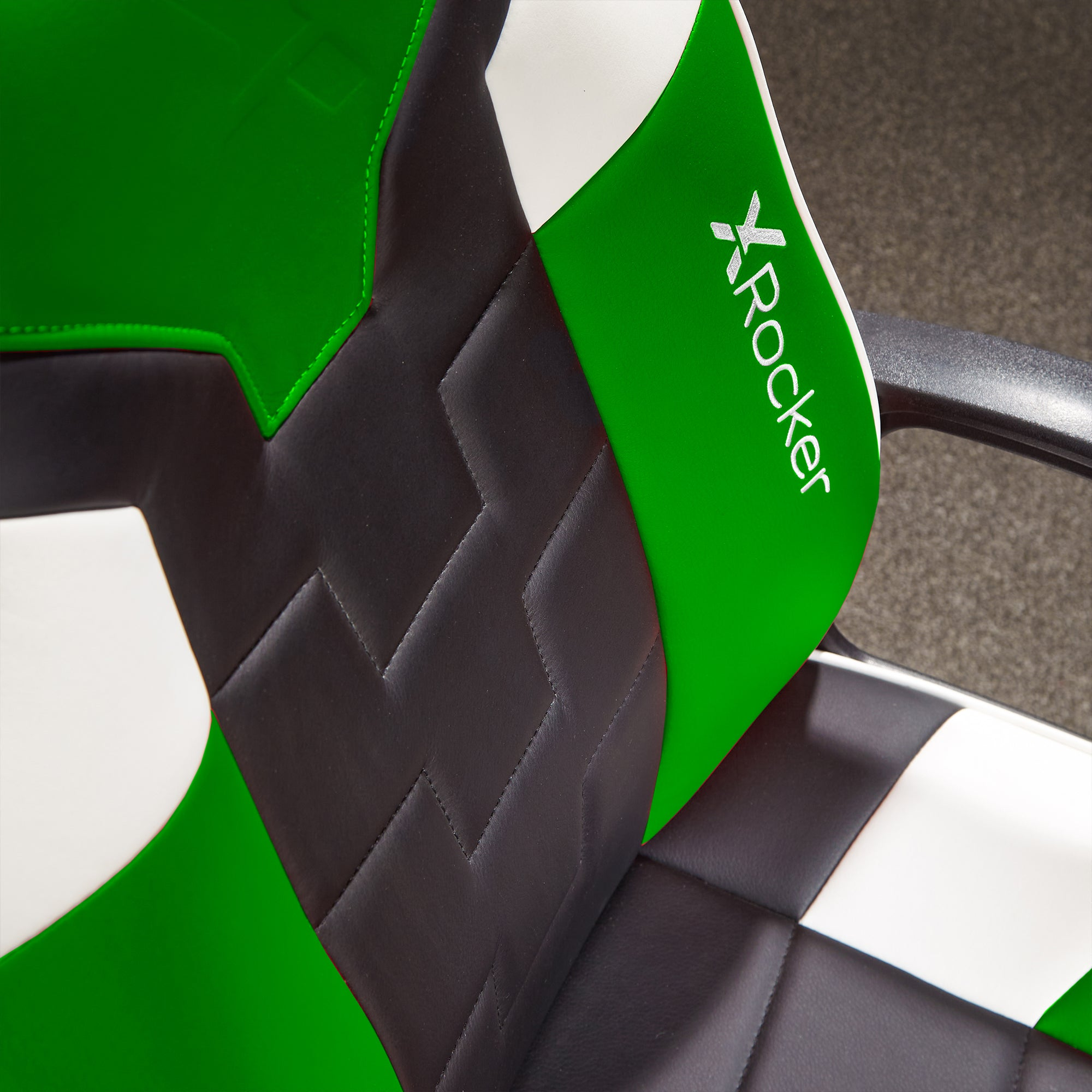 Nahaufnahme eines grünen, schwarzen und weißen Gaming-Stuhls mit "X Rocker"-Logo.